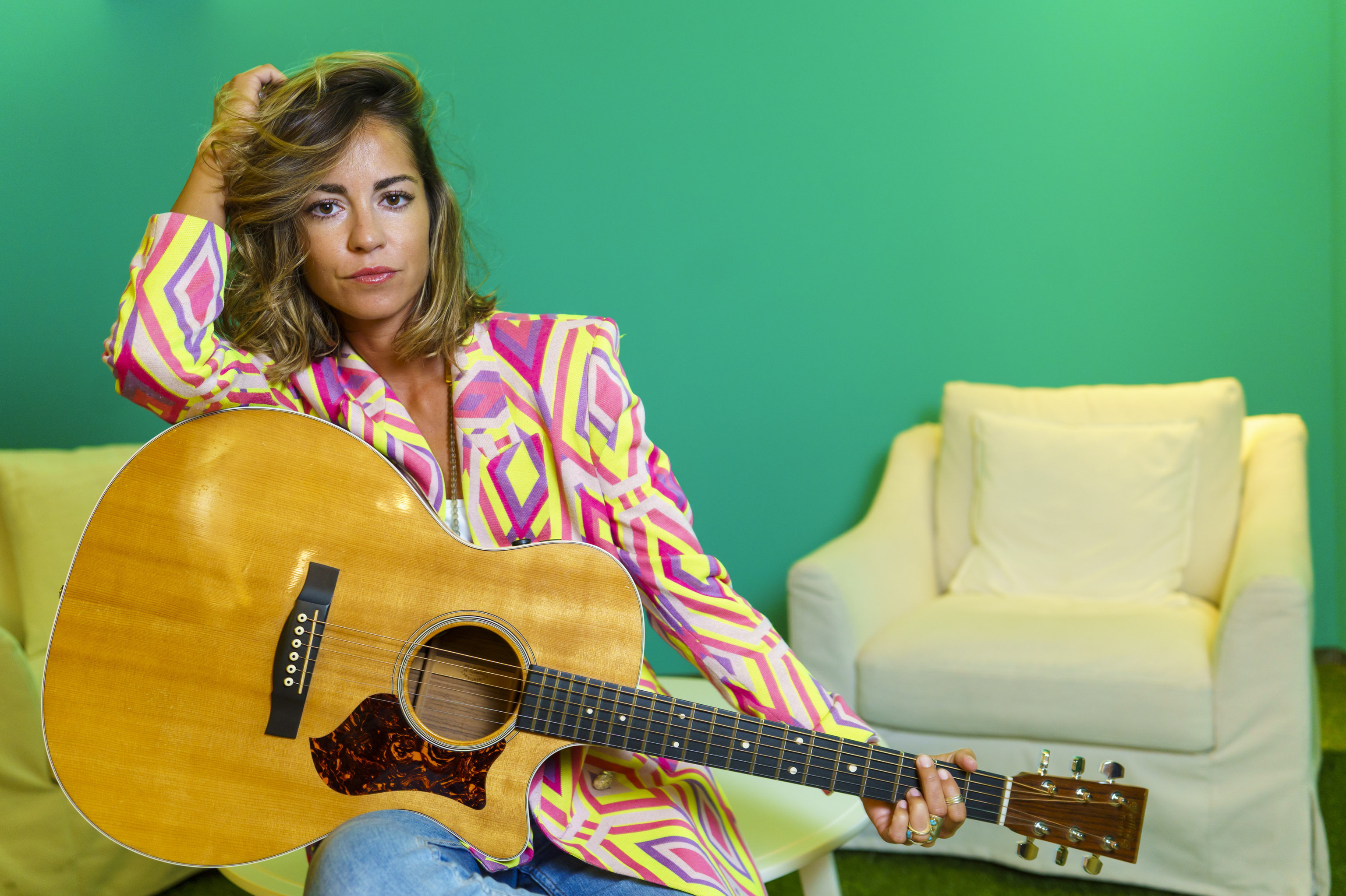 La artista, de 29 aos, posa con su inseparable guitarra y una colorida americana de rombos.