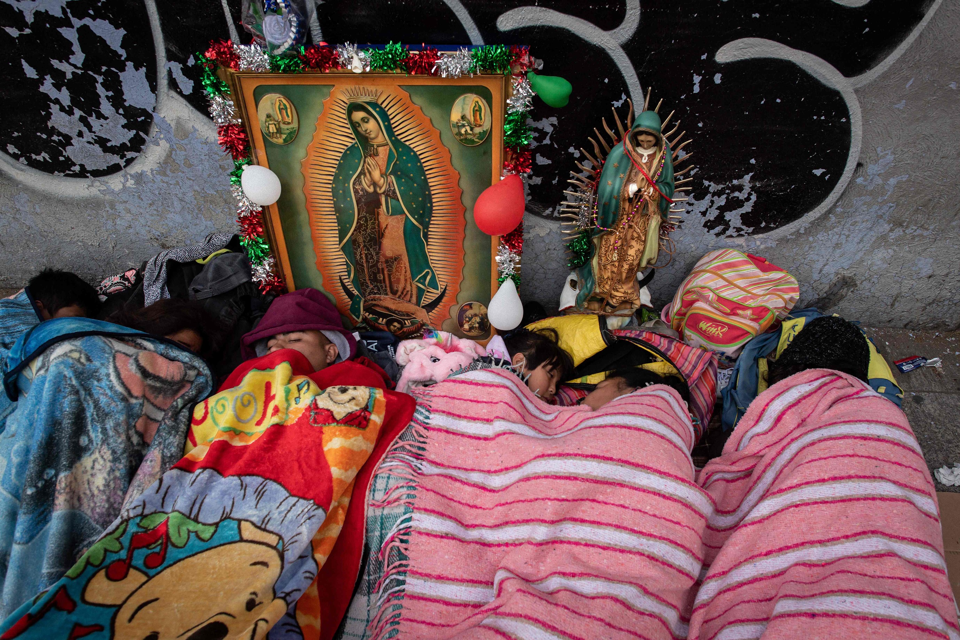 Peregrinos duermen en las calles cerca de un retrato de la Virgen de Guadalupe.
