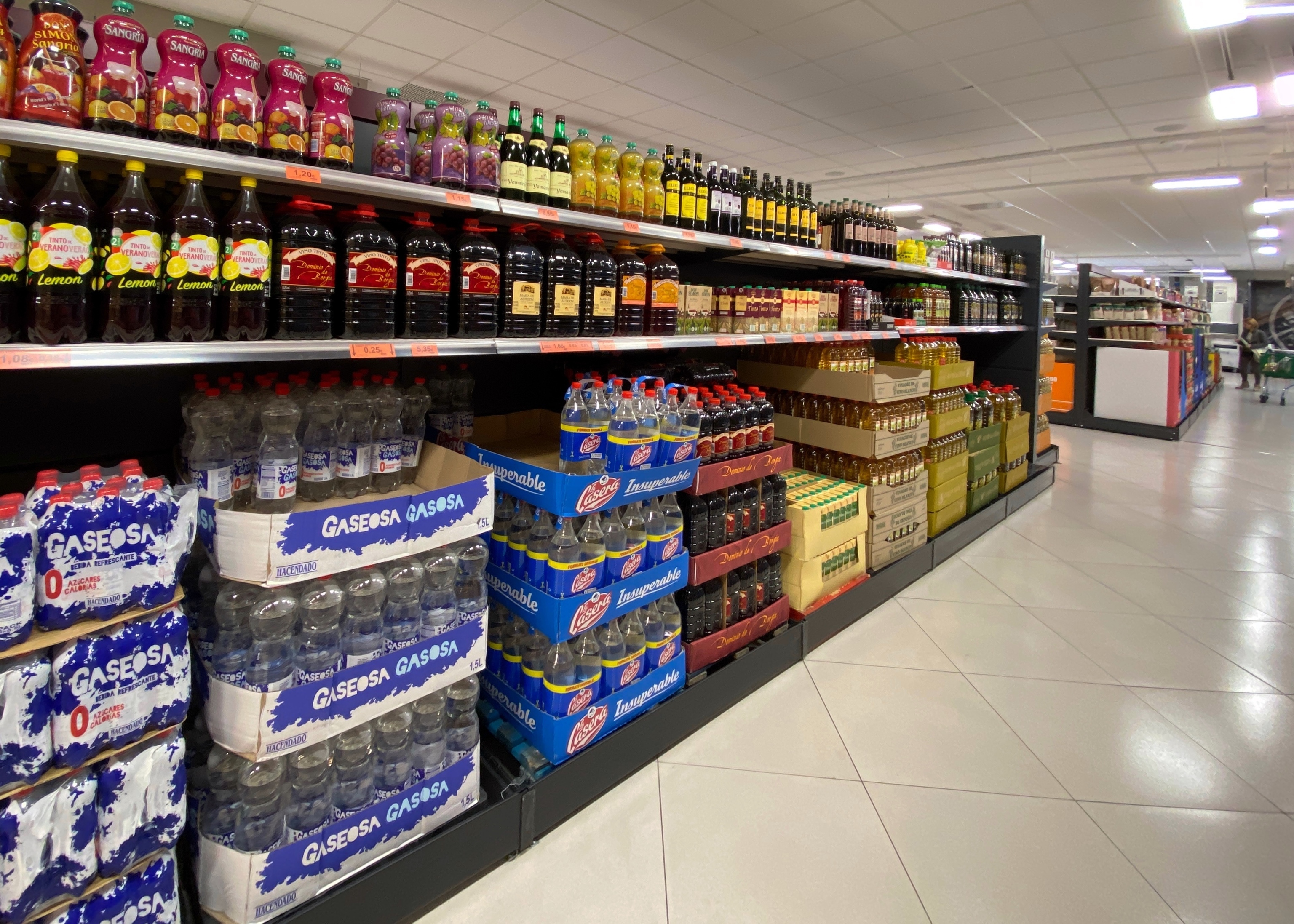 Un pasillo de un supermercado de Madrid con botellas de vino, gaseosa y aceite.