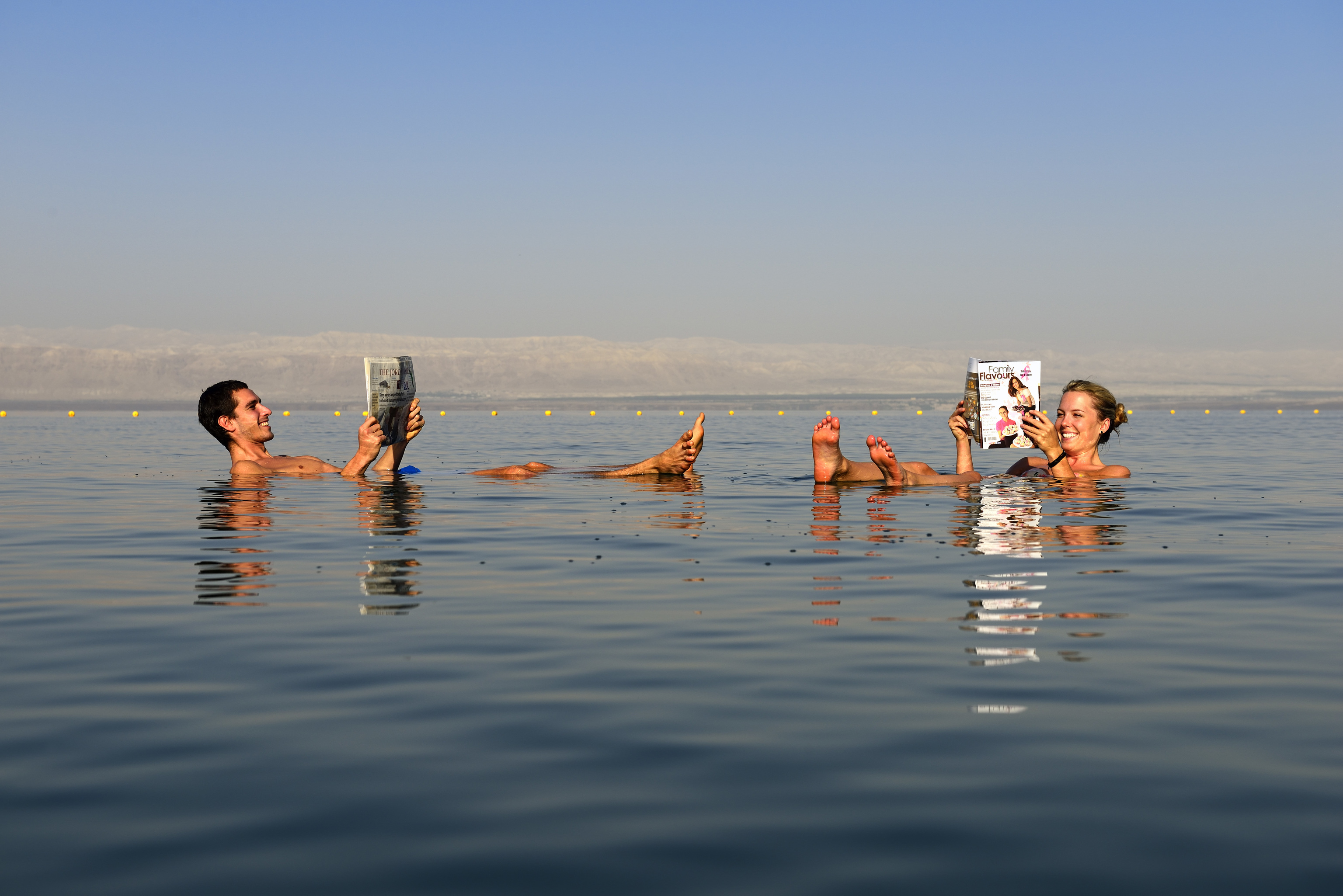 Dos jóvenes leen el periódico en el mar Muerto.