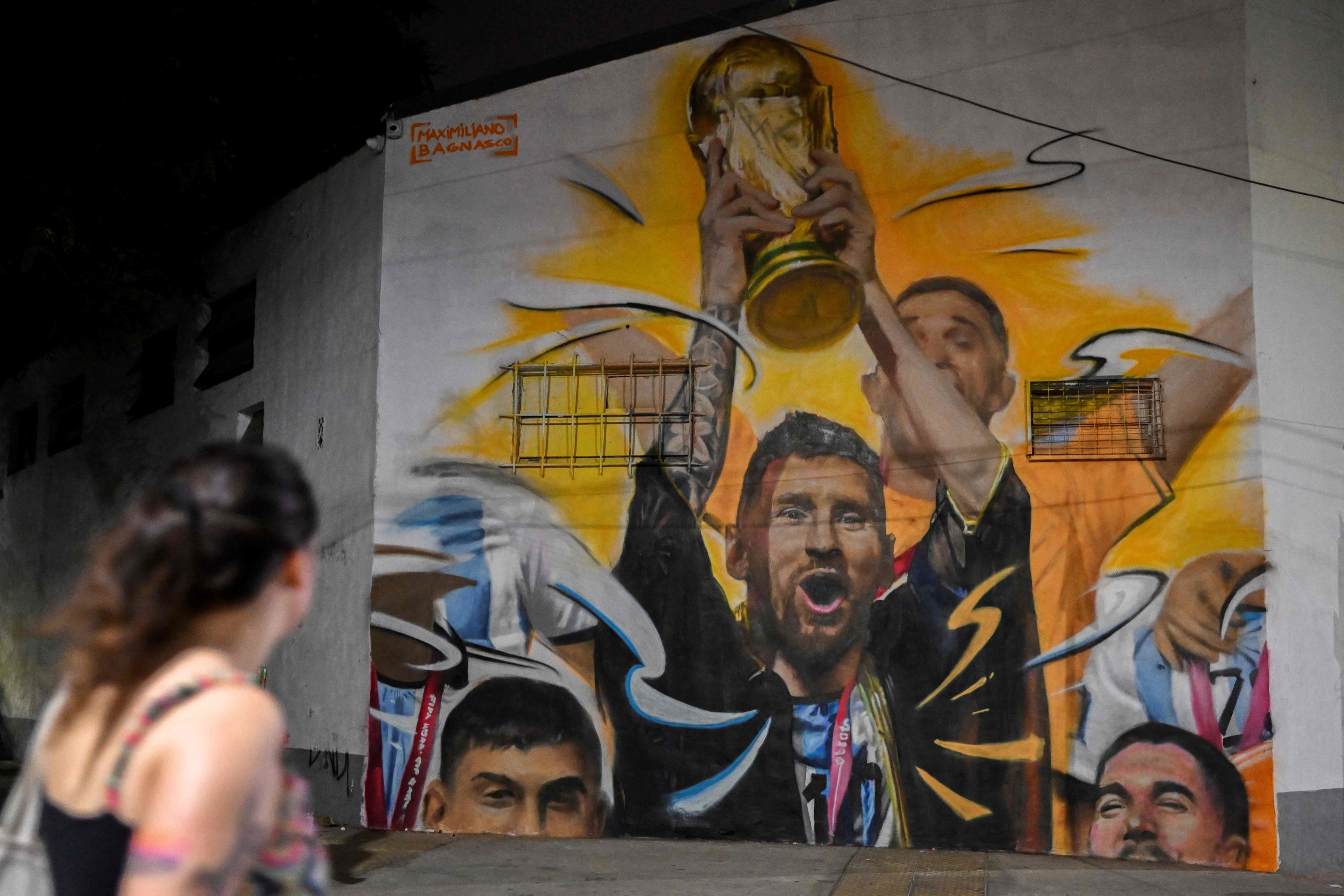 Una mujer pasea delante de un mural de Messi en Buenos Aires.