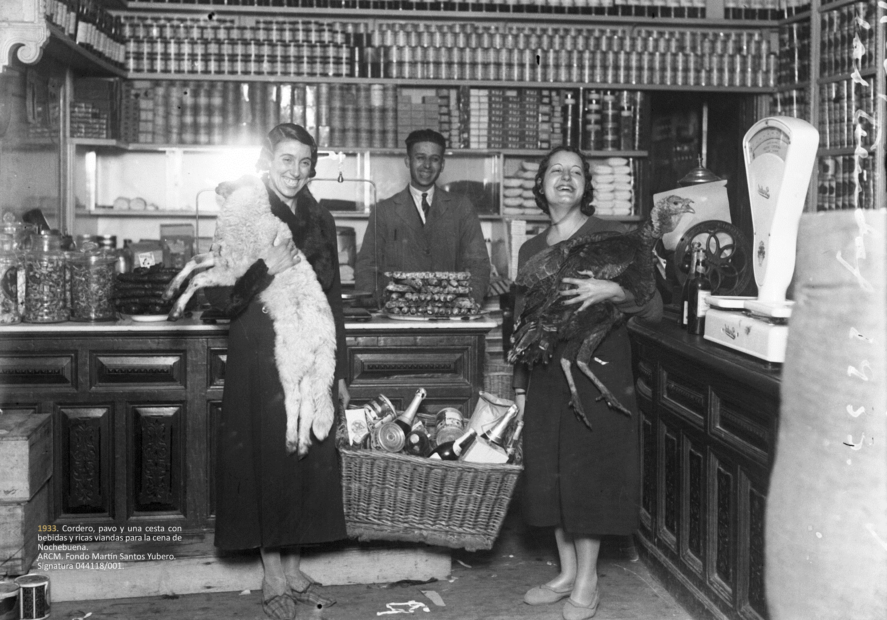 Dos mujeres sujetan, en 1933, un cordero, un pavo y una cesta con viandas para la cena de Nochebuena.