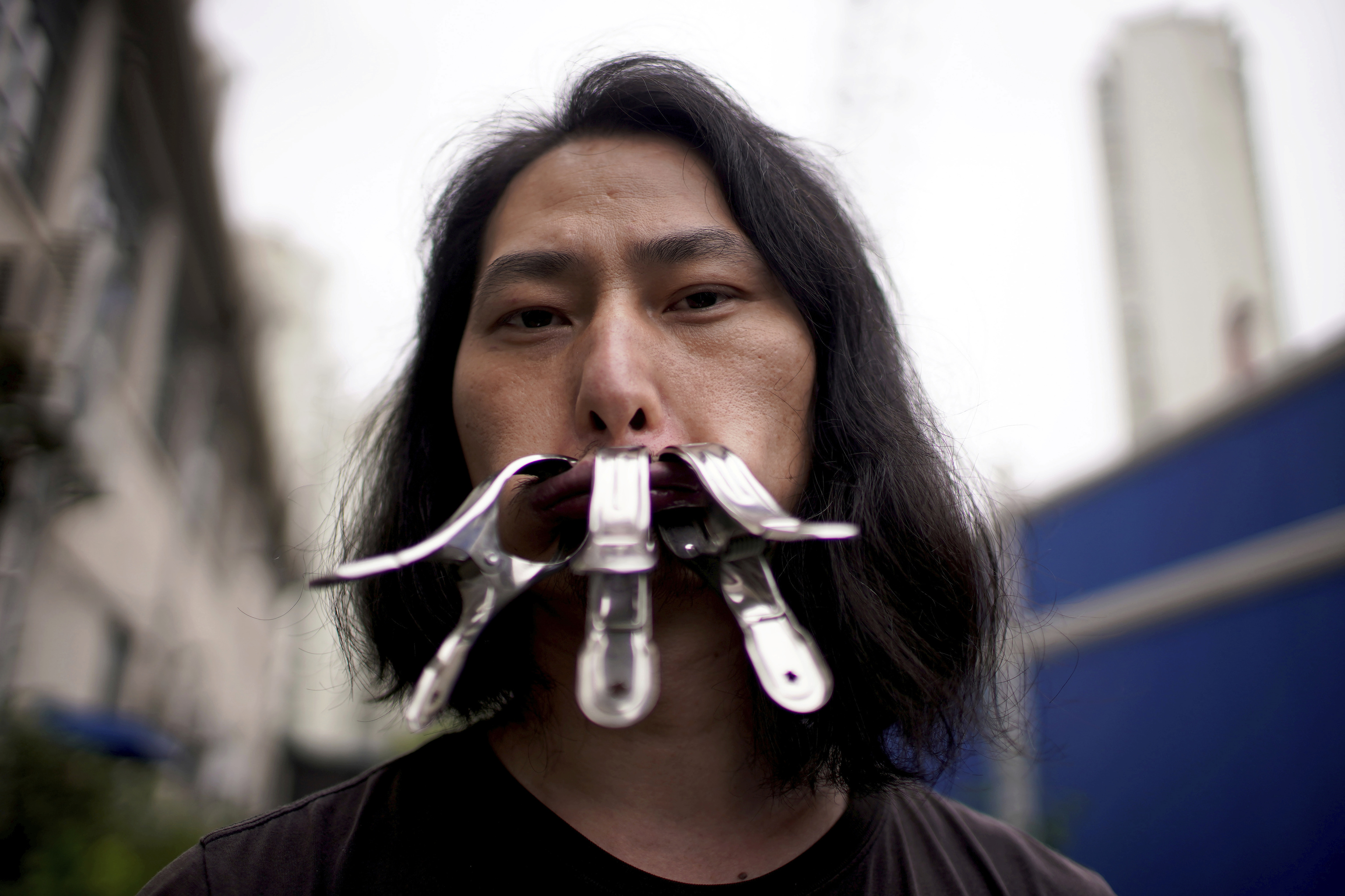 El artista chino 'Brother Nut' posa con la boca cerrada con pinzas.