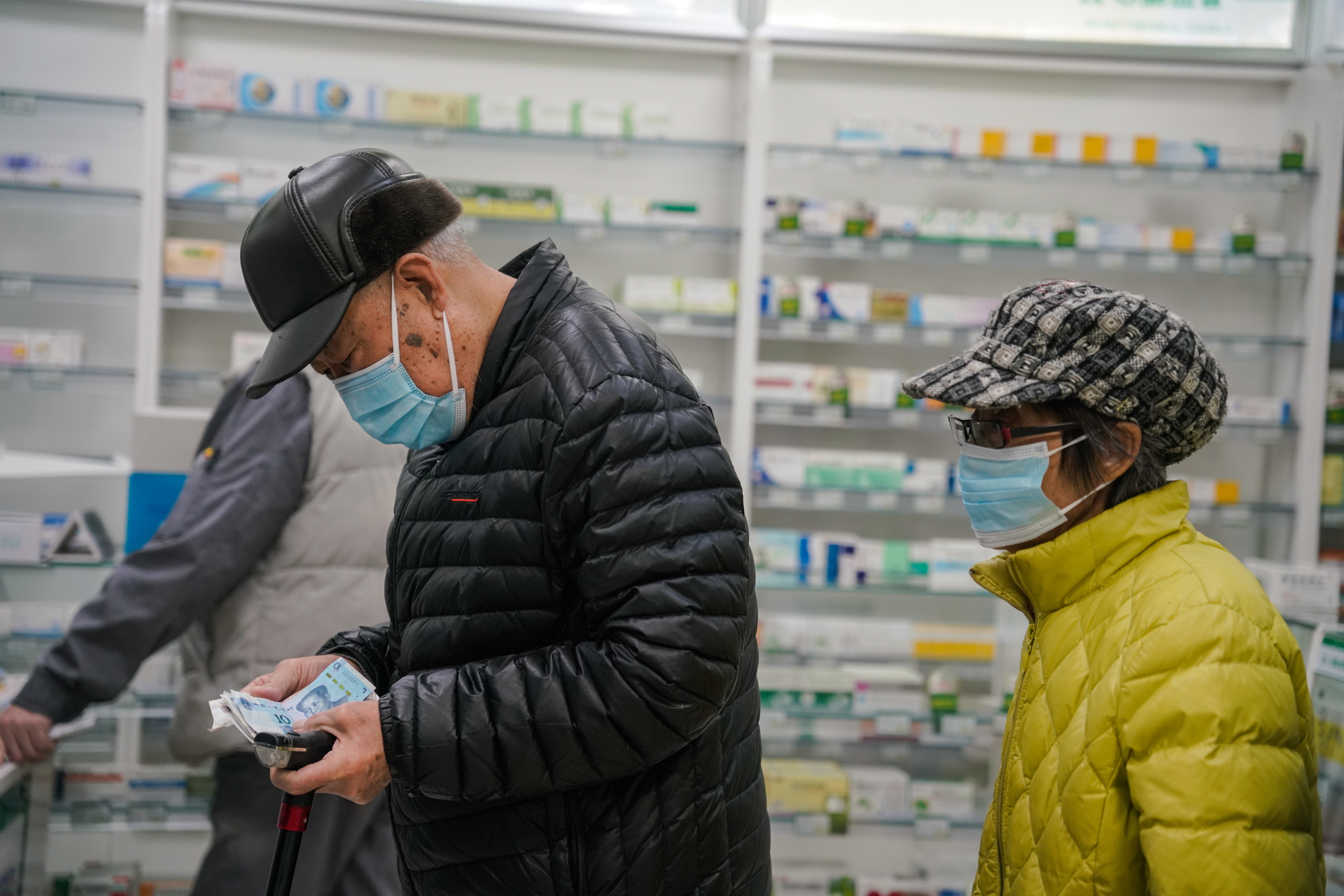 Unas personas con mascarillas compran medicamentos en una farmacia de Pekín.