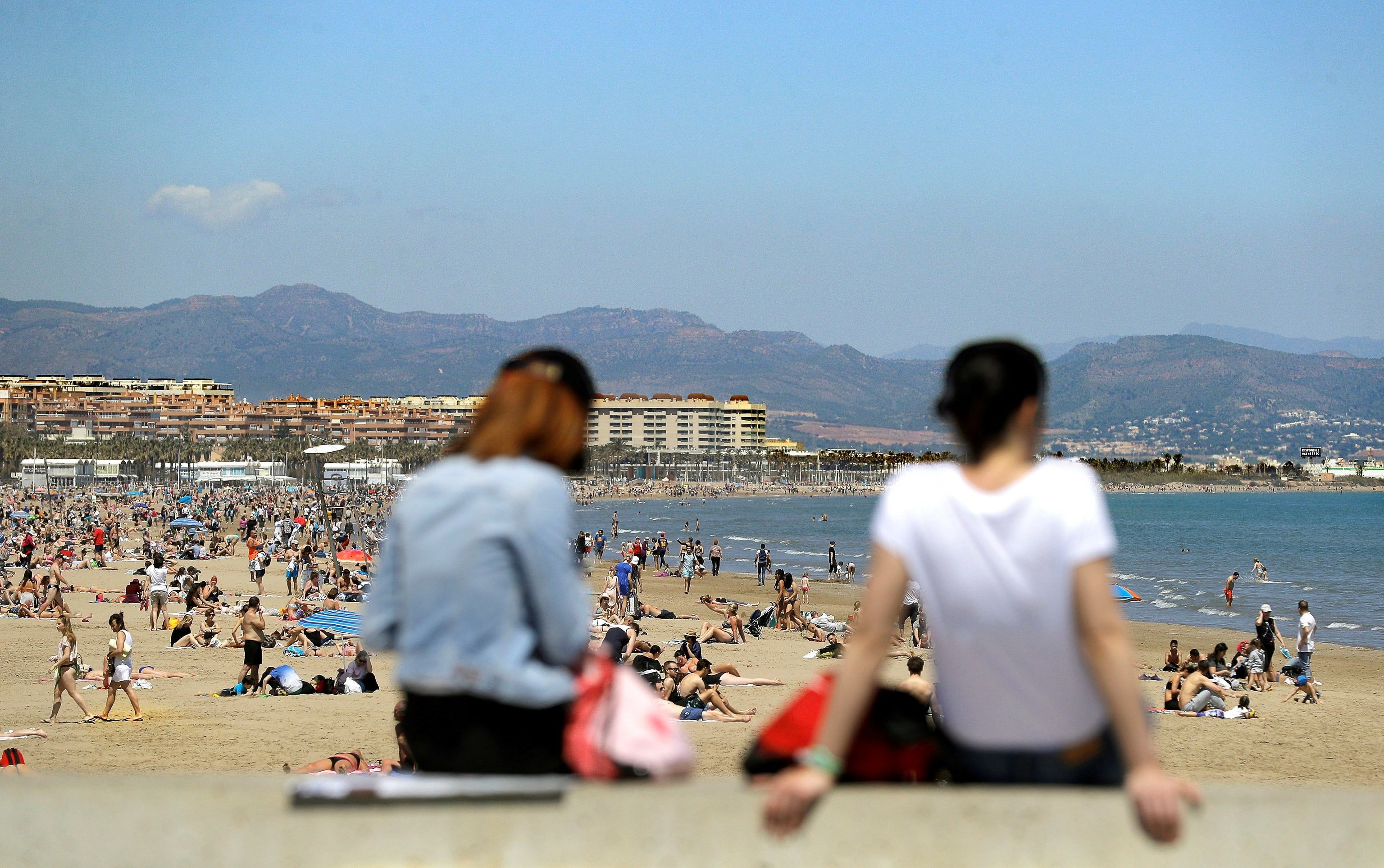 Dos turistas toman el sol en la playa de la Malvarrosa de Valencia.