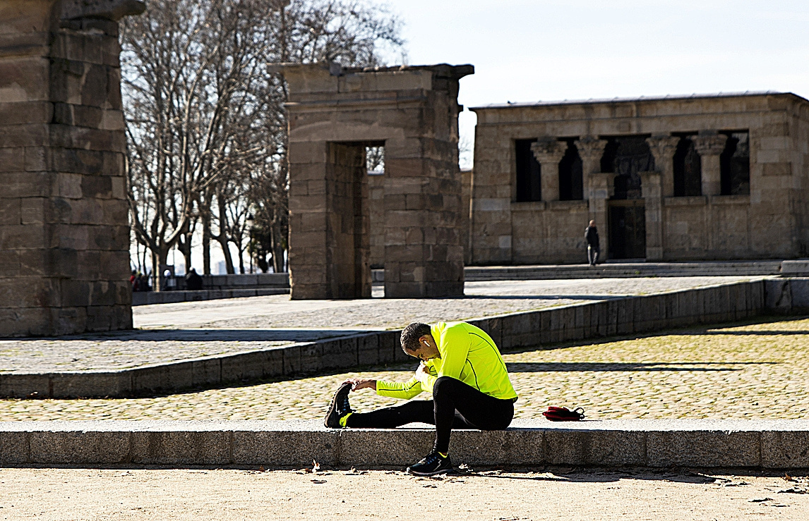 Un hombre realiza estiramientos frente al Templo de Debod, junto al paseo del Pintor Rosales.