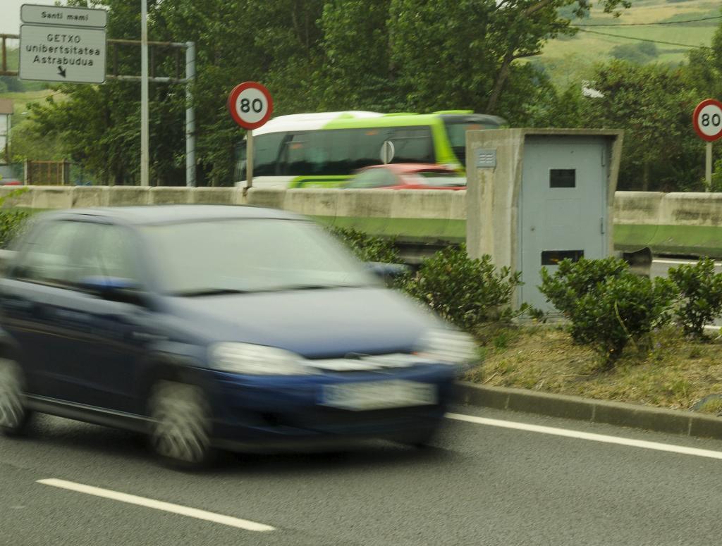 Un coche pasa junto a un radar de trfico en una carretera.