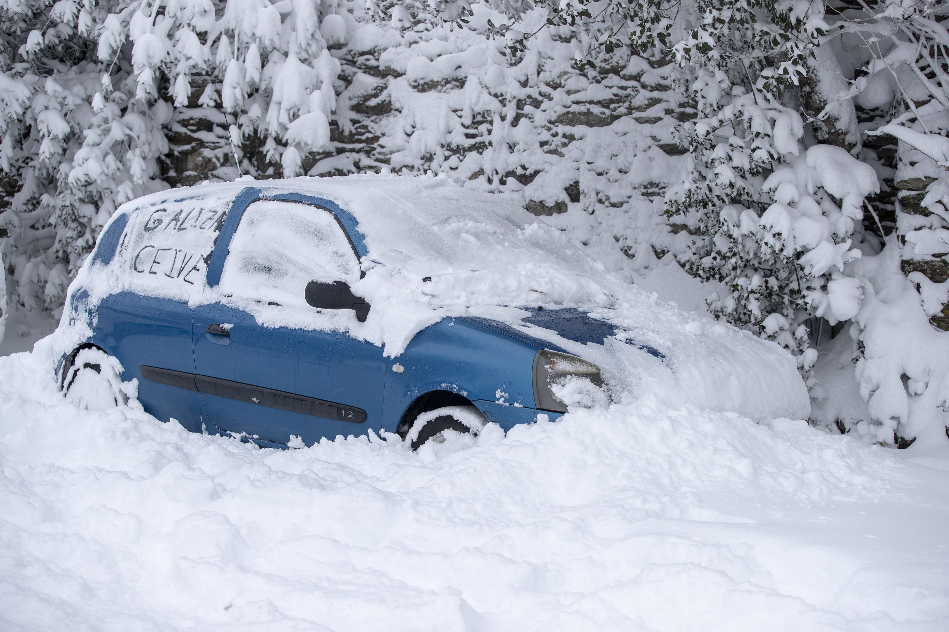 La nieve sepulta a varios vehículos que permanecen estacionados, este miércoles en Pedrafita do Cebreiro, Lugo. El primer gran temporal del invierno en España, por el paso de la borrasca Fien, ha cubierto este miércoles de nieve la mitad norte peninsular, lo que dificulta el tráfico en diversas vías.