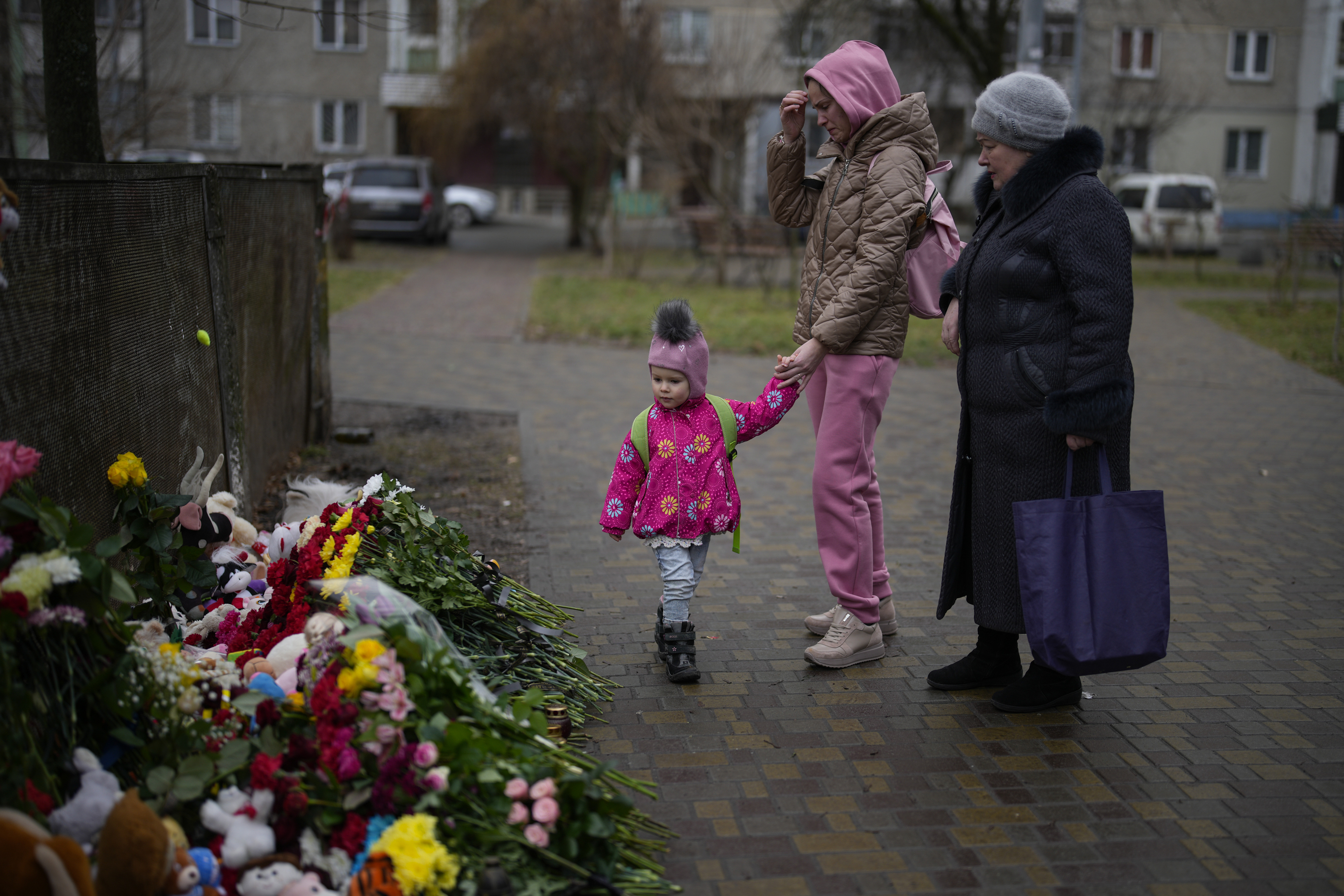 Varias personas presentan sus respetos en el lugar donde un helicptero se estrell el mircoles contra una infraestructura civil, en Brovary, en las afueras de Kiev, Ucrania, viernes 20 de enero de 2023.