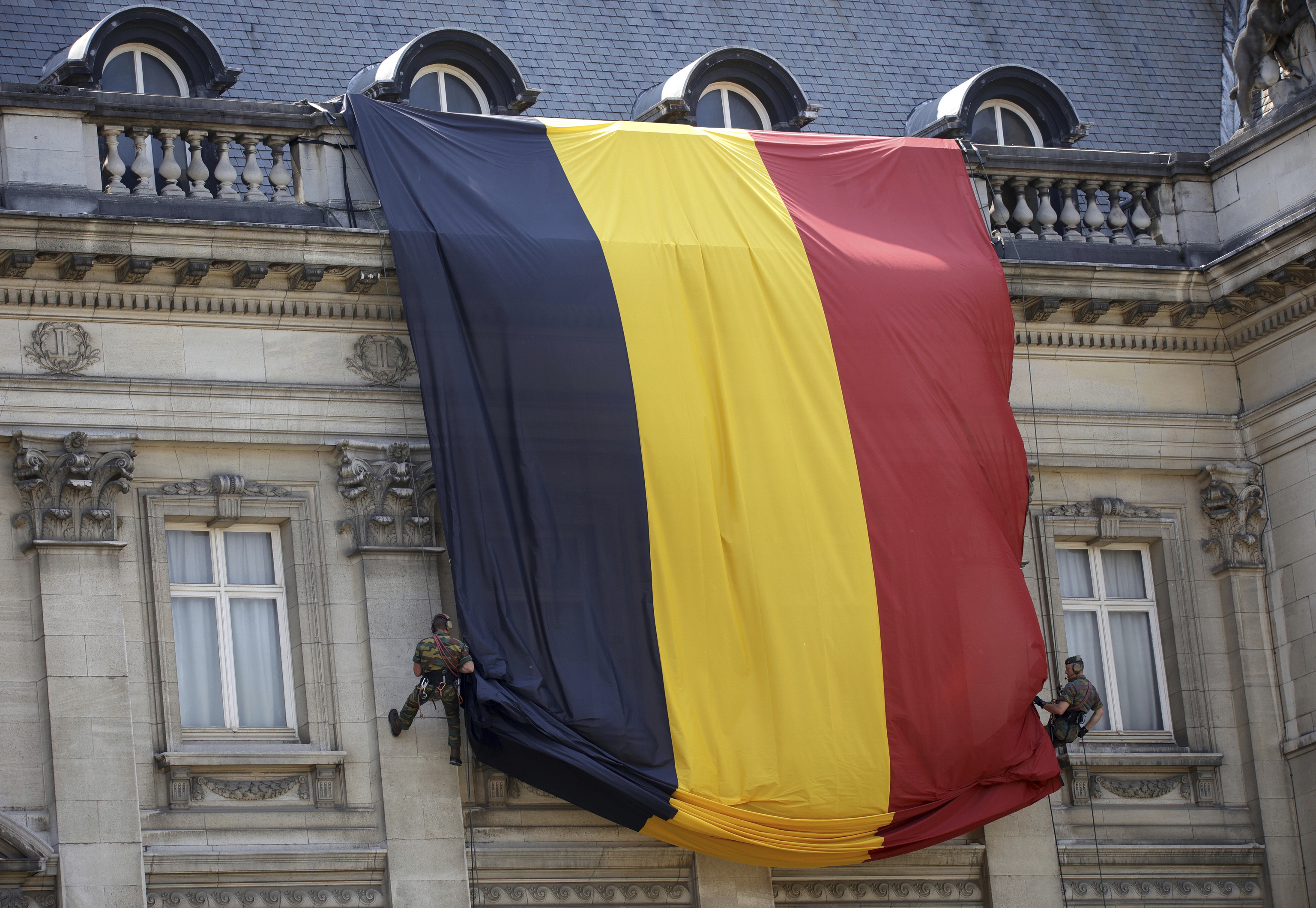 Soldados despliegan una bandera belga en el Palacio Real de Bruselas
