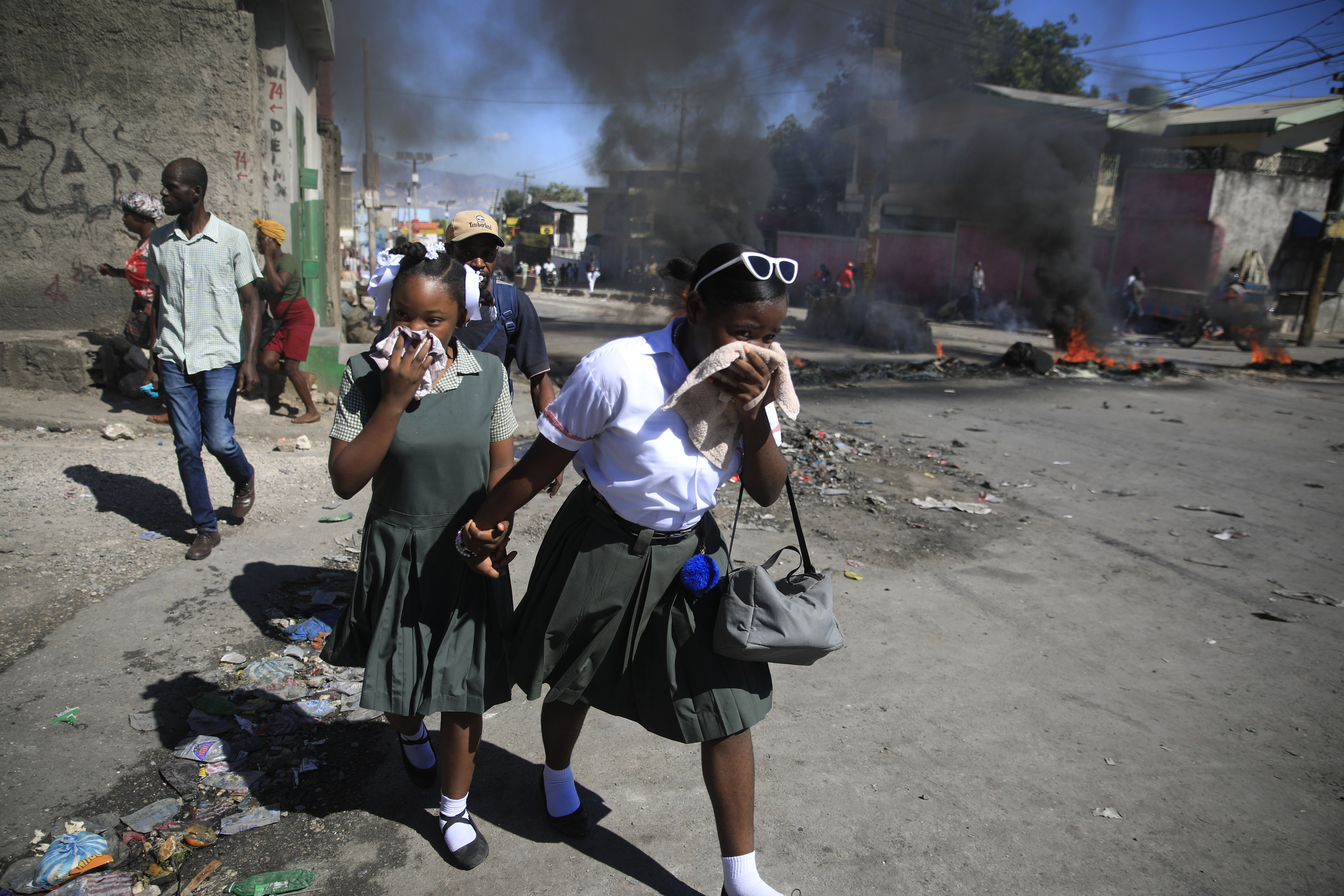 Estudiantes pasan una barricada incendiada por las protestas de la policía, en Puerto Príncipe.