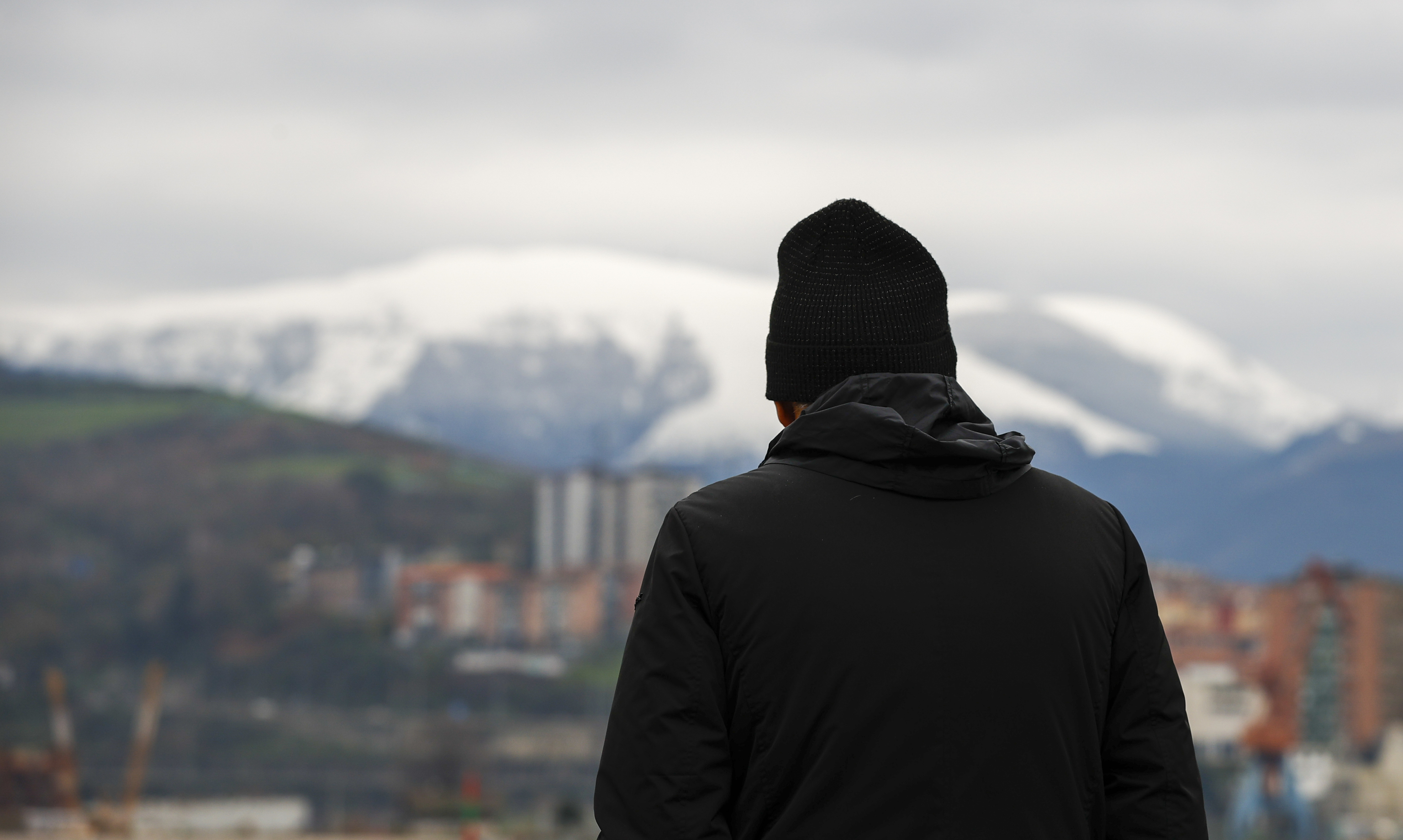 Una persona pasea abrigada con el monte Ganekorgorta nevado situado al sur de Bilbao