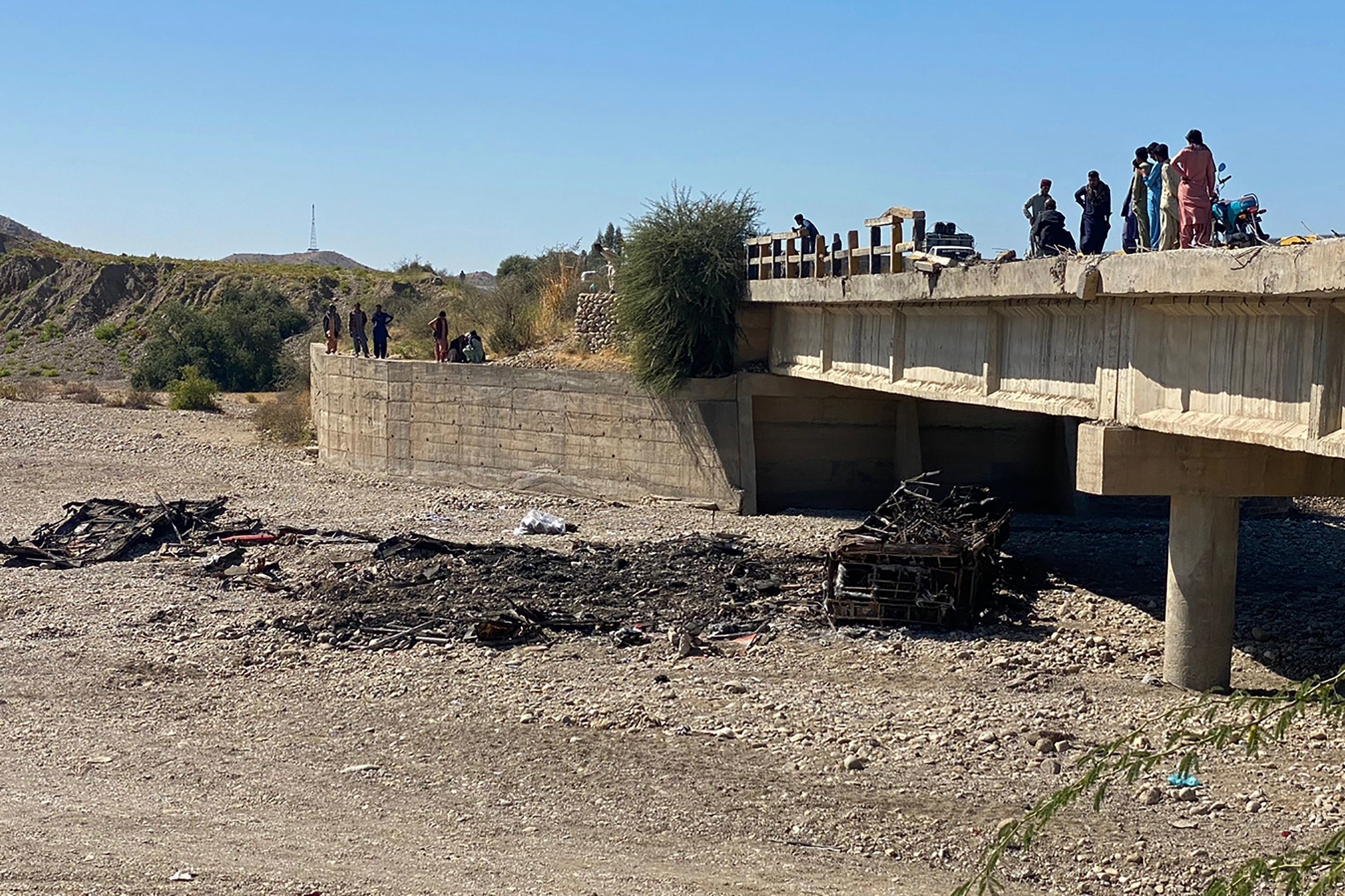 Los residentes se renen sobre un puente para observar los restos de un autobs de pasajeros incendiado en el distrito de Lasbela, en la provincia paquistan de Baluchistn, el 29 de enero de 2023. - Al menos 40 personas murieron cuando un autobs se precipit por un puente en el suroeste de Pakistn y estall en llamas, inform un funcionario del gobierno el 29 de enero.