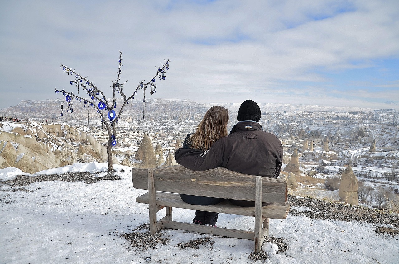 Un pareja de enamorados contemplando el paisaje nevado desde un banco.