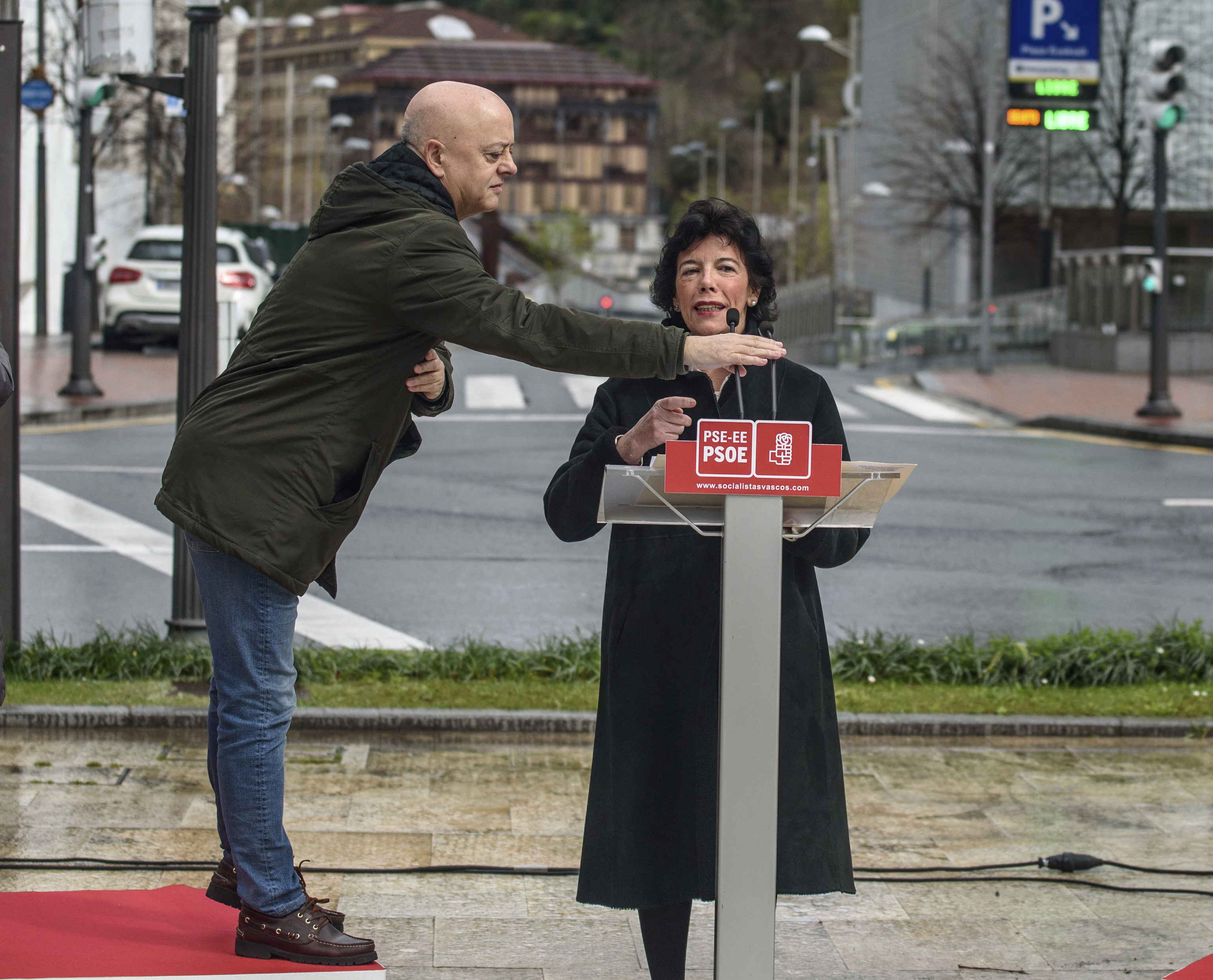 Odón Elorza ajusta los micrófonos a la altura de la ex ministra Isabel Celaá durante la campaña de las elecciones generales de 2019.