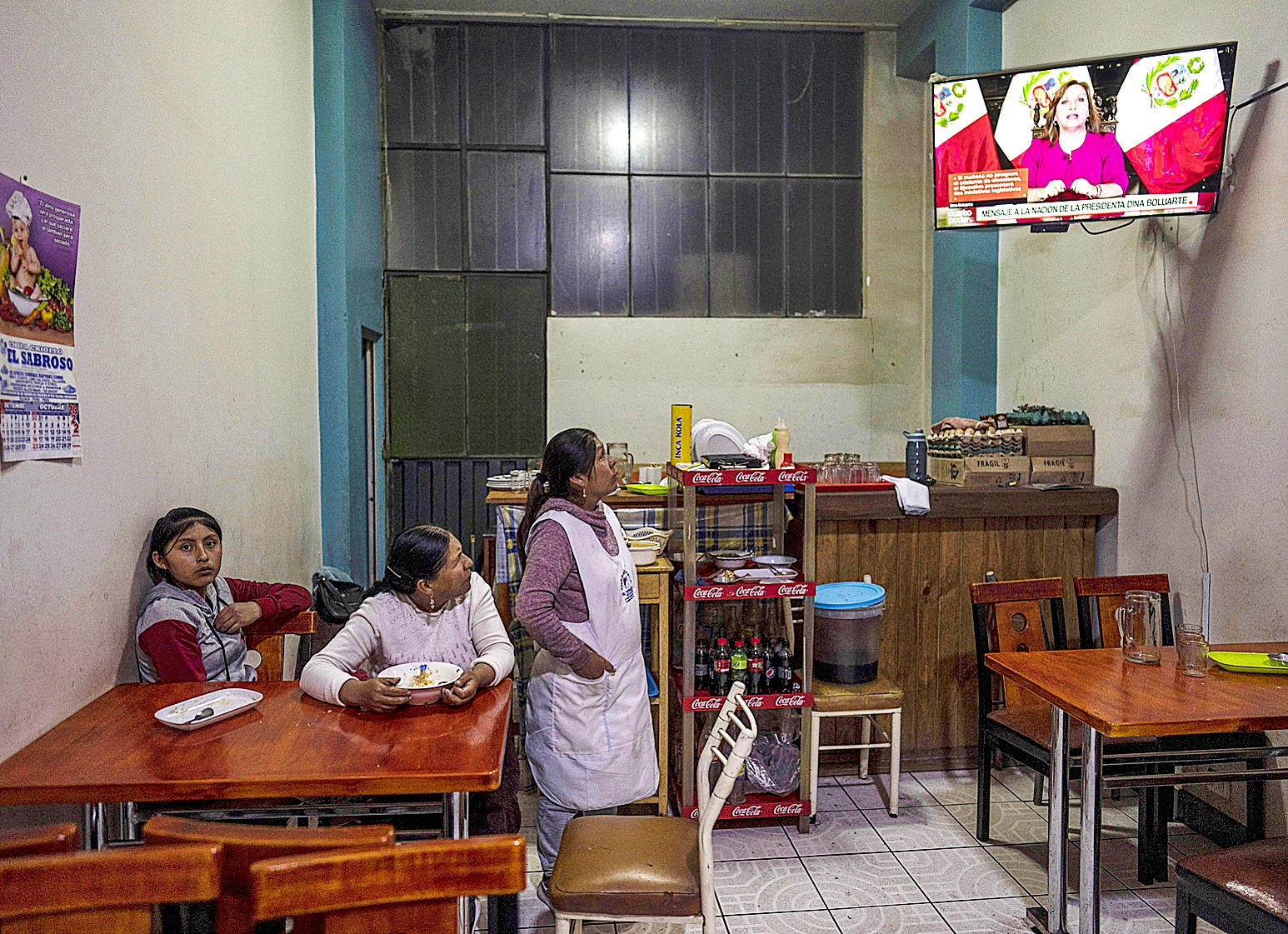 Mujeres peruanas observan por televisión el mensaje de la presidenta, Dina Boluarte, en Juliana.