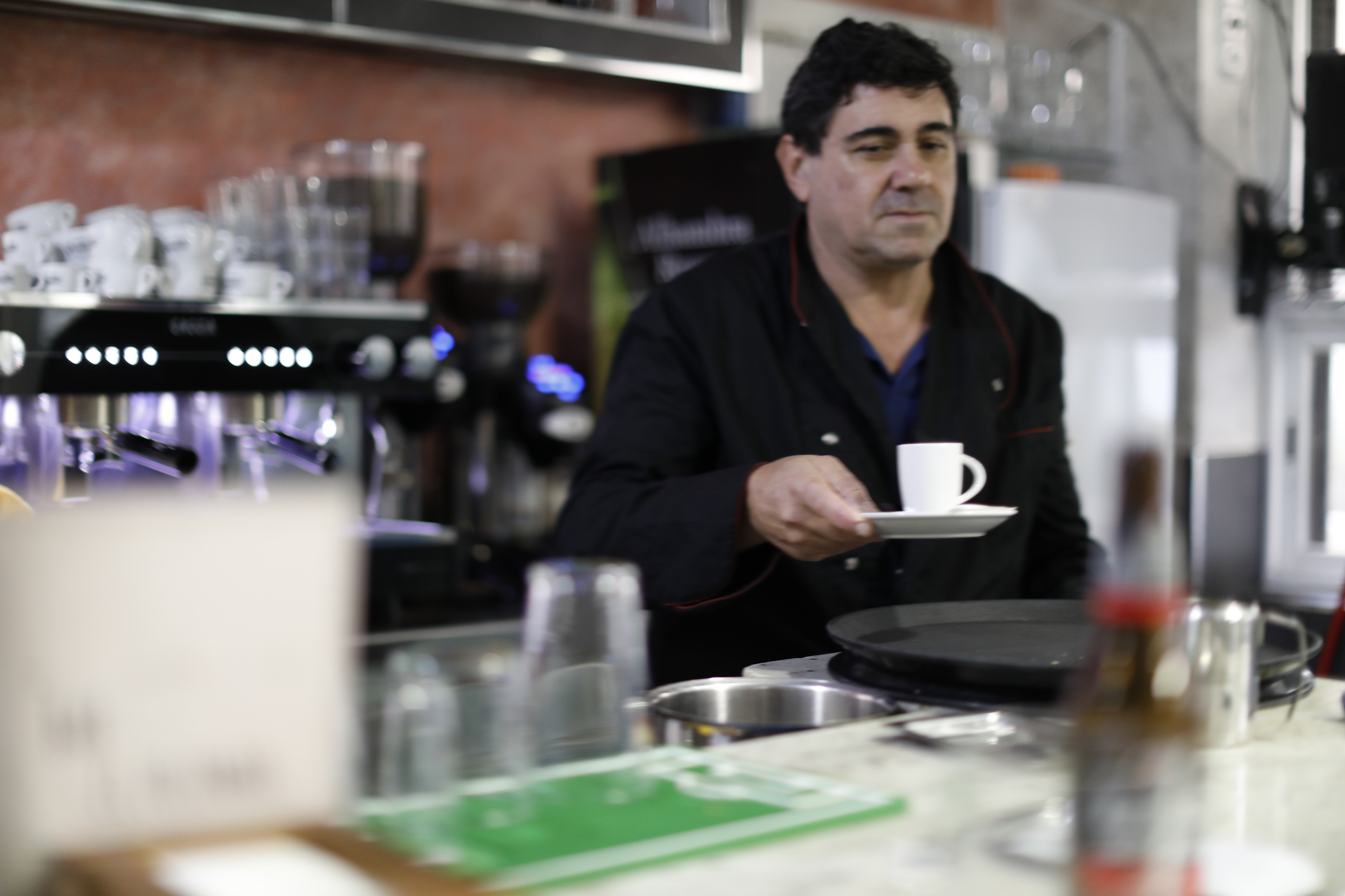 Un camarero sirve un café en un bar