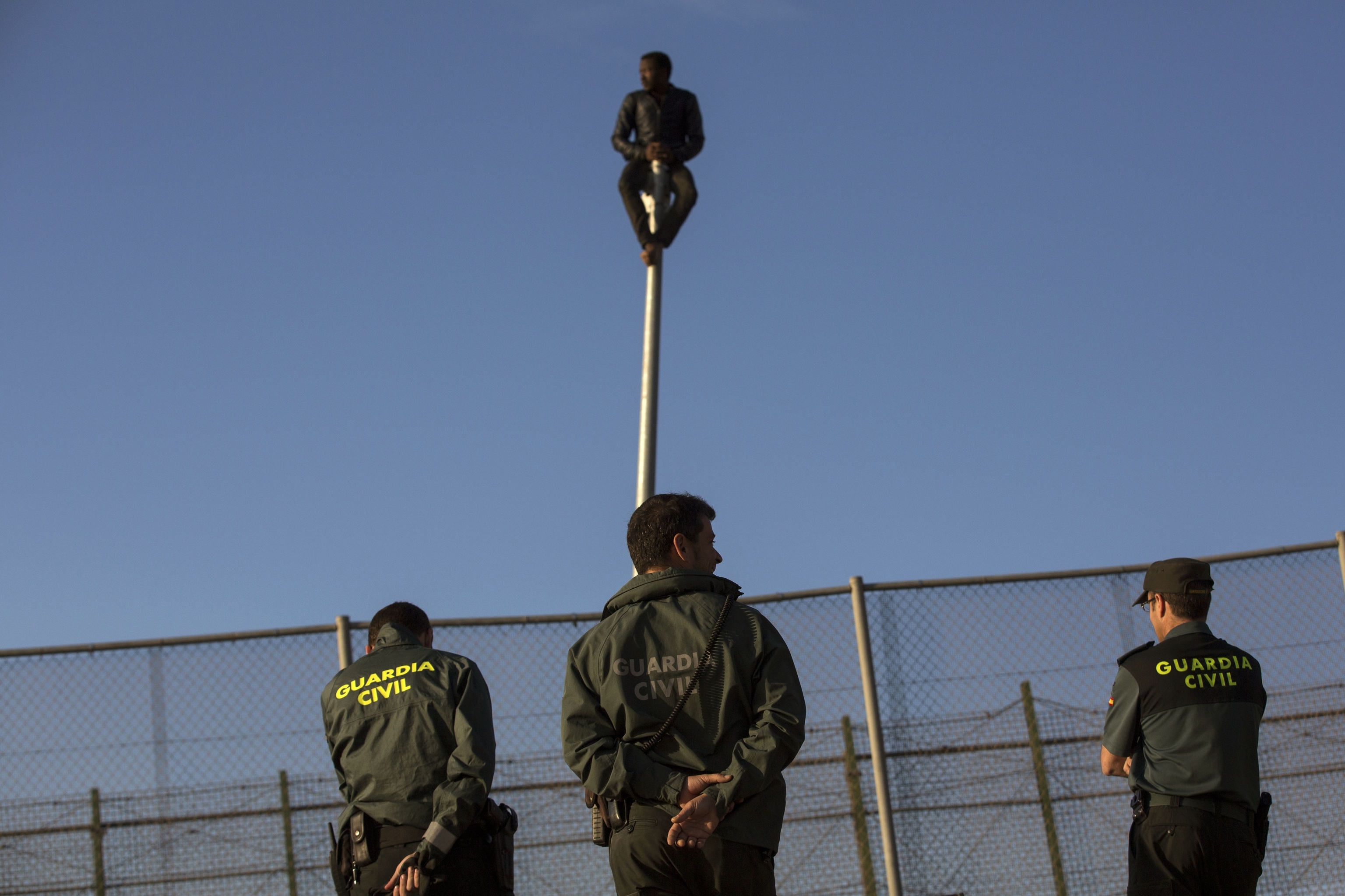 Tres agentes de la Guardia Civil vigilan la valla de Melilla.