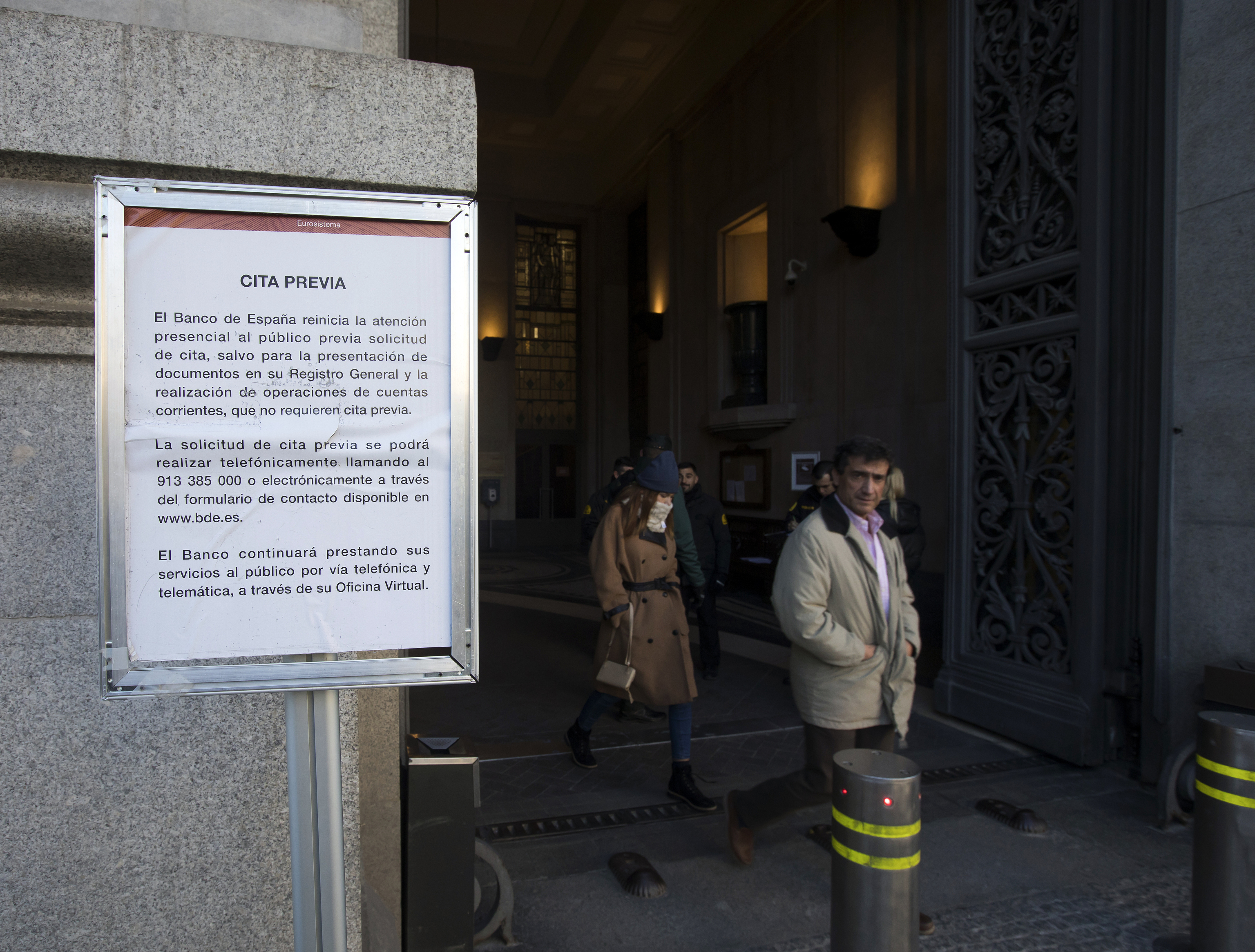 Un cartel anuncia la obligación de cita previa en la puerta del Banco de España.