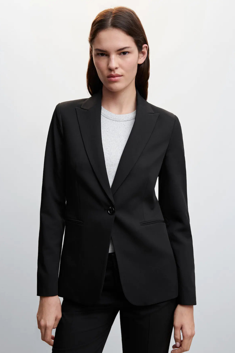 Outfit de oficina. Chica usando un pantalón negro, una blusa color café y  un saco color marfil