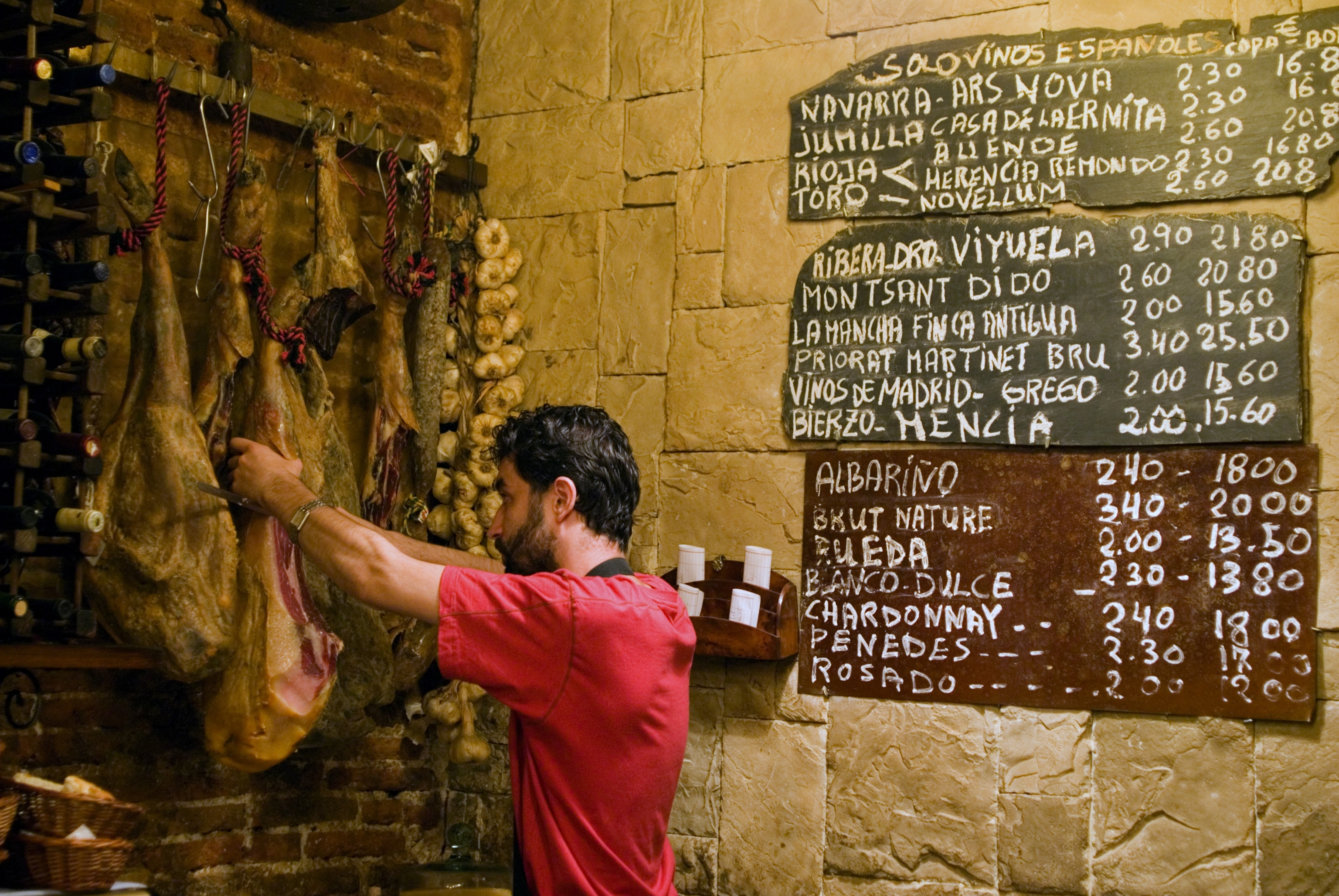 Un camarero corta jamón en una barra de Madrid.