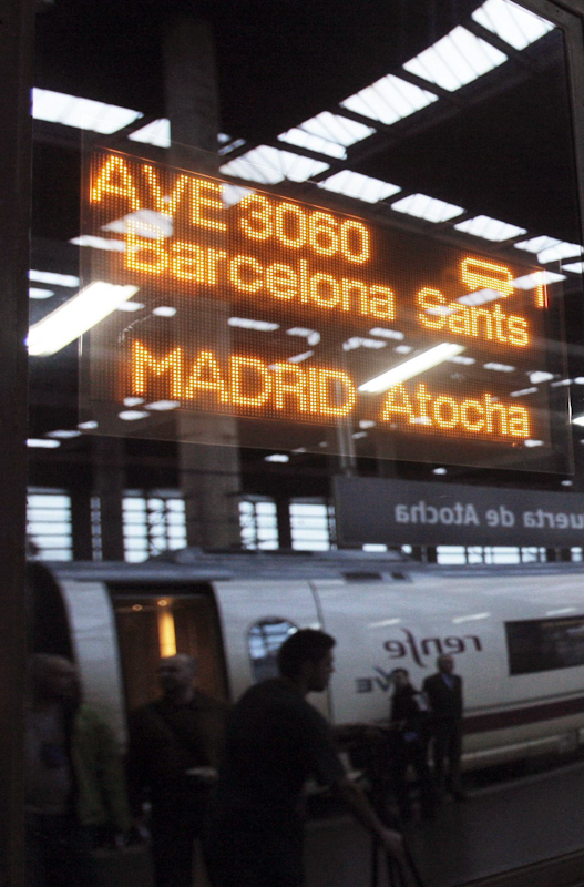 El primer AVE llegado desde Barcelona reflejado en un cartel en la estación de Atocha.