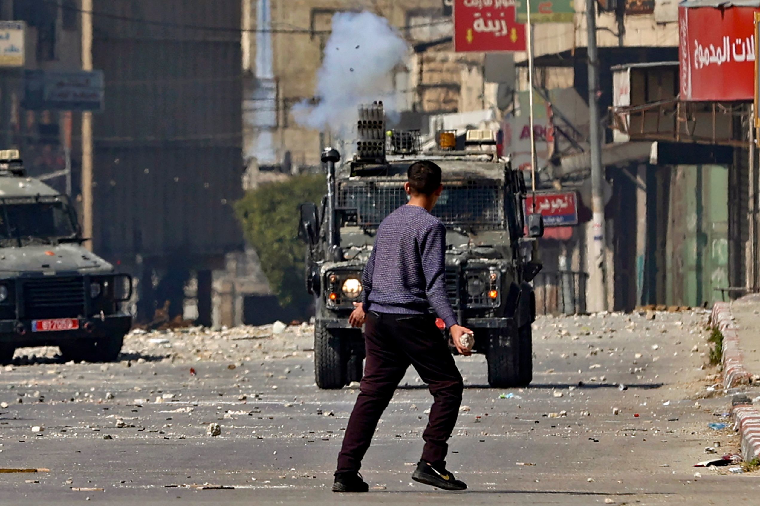 Un palestino frente a militares israeles, en Nablus.