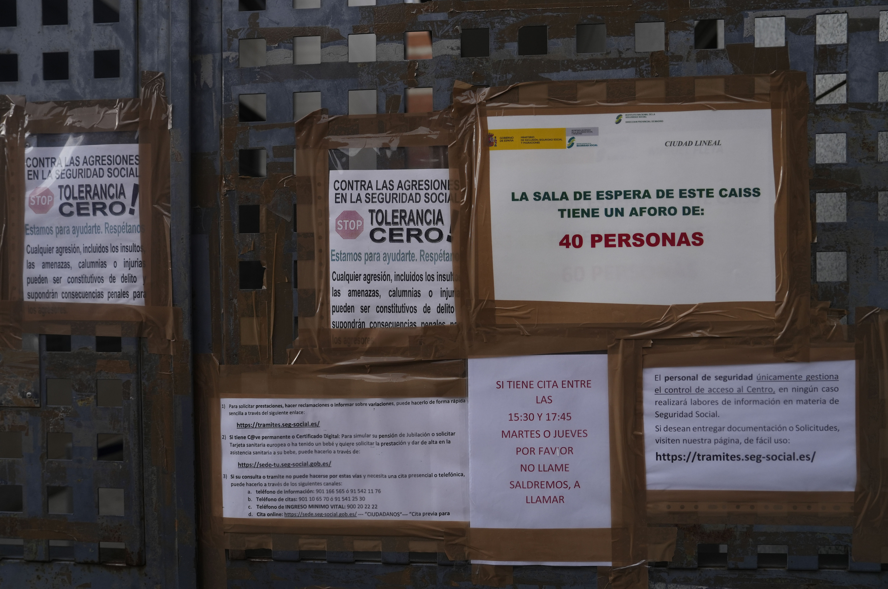 Carteles instalados en la puerta de entrada a la oficina de la Seguridad Social en Ciudad Lineal, Madrid.