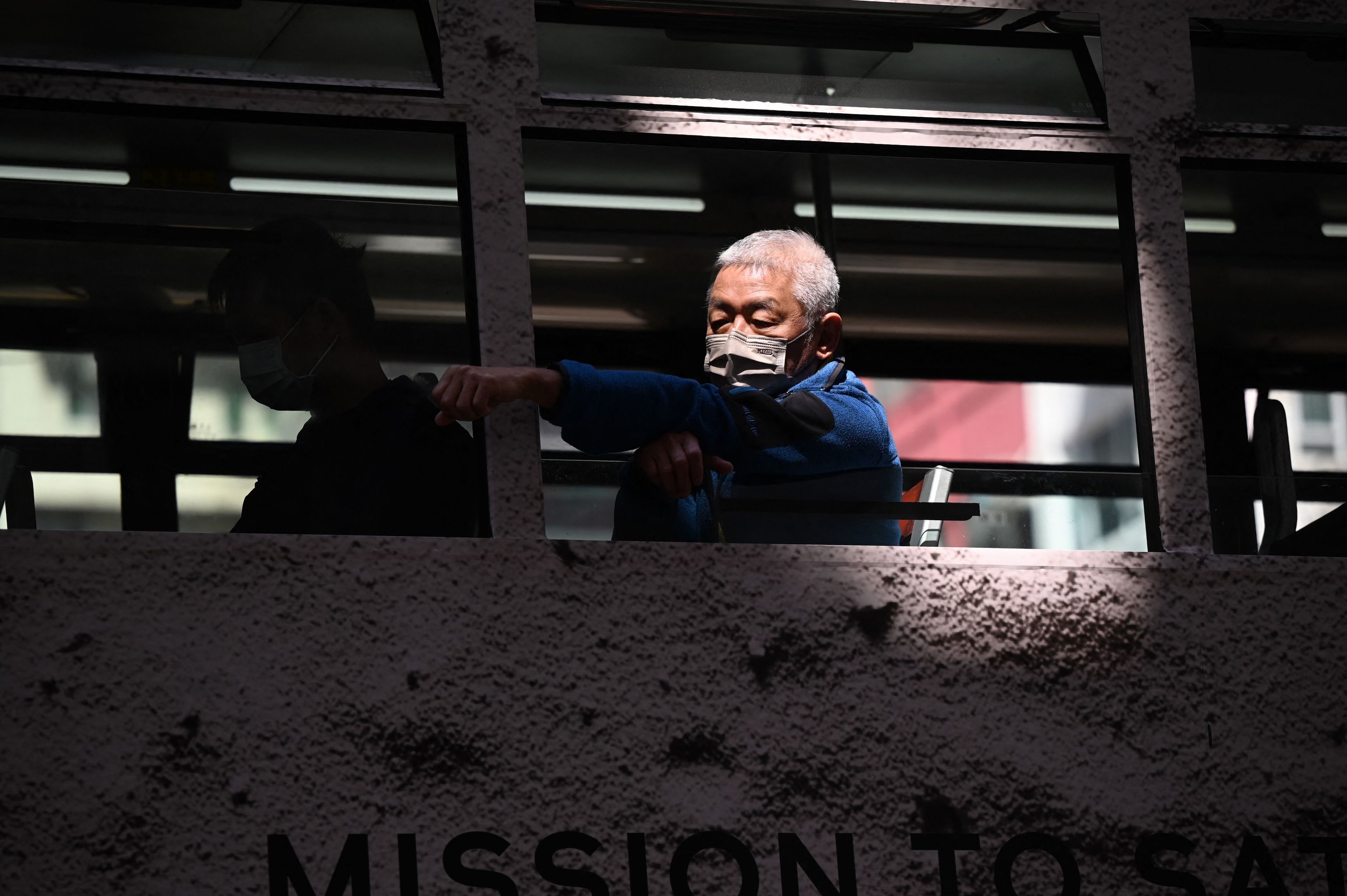 Un hombre viaja en un tranva con mascarilla en Hong Kong.
