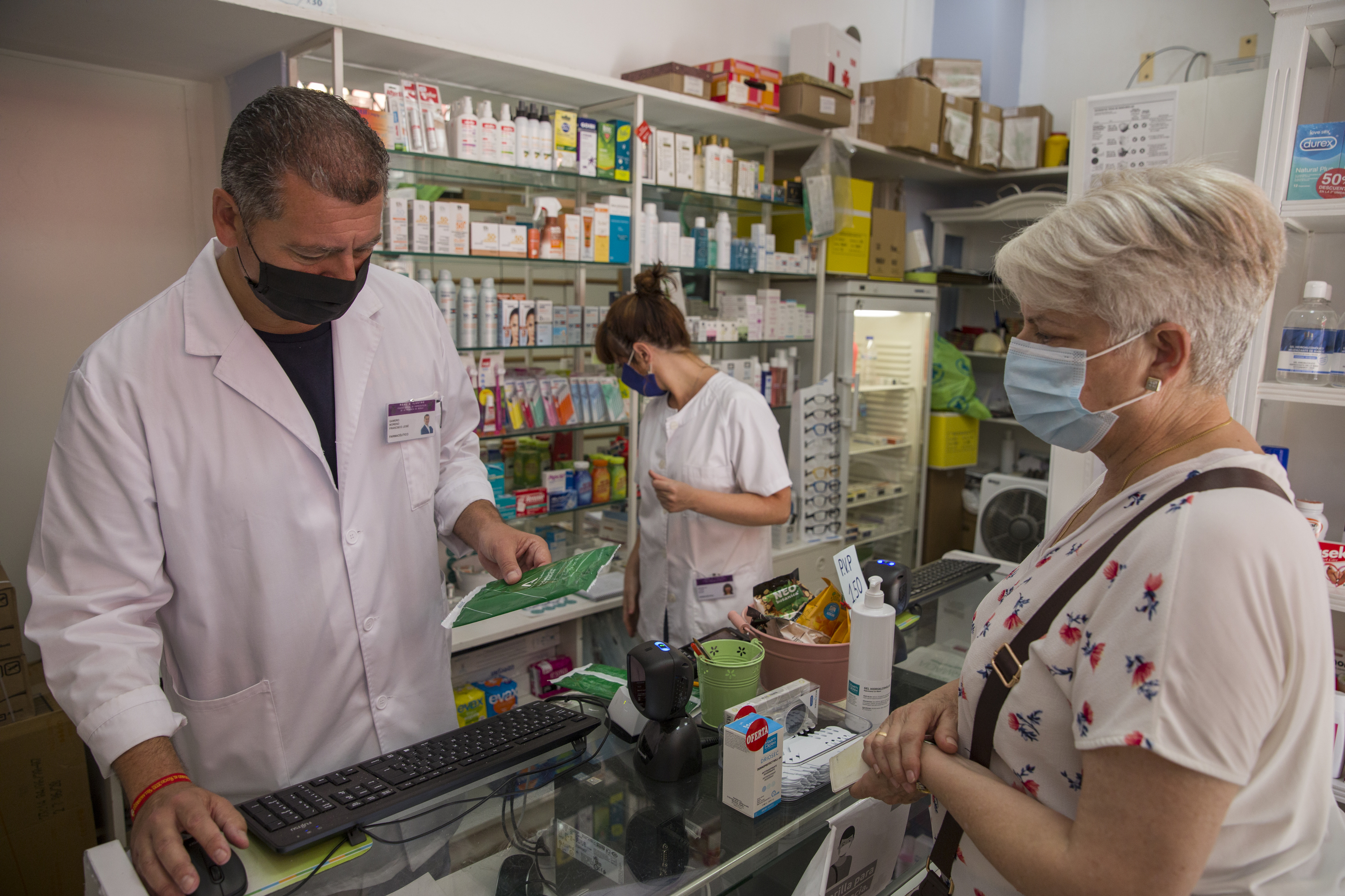Un farmacutica atiende a una usuaria en una farmacia de Sevilla.