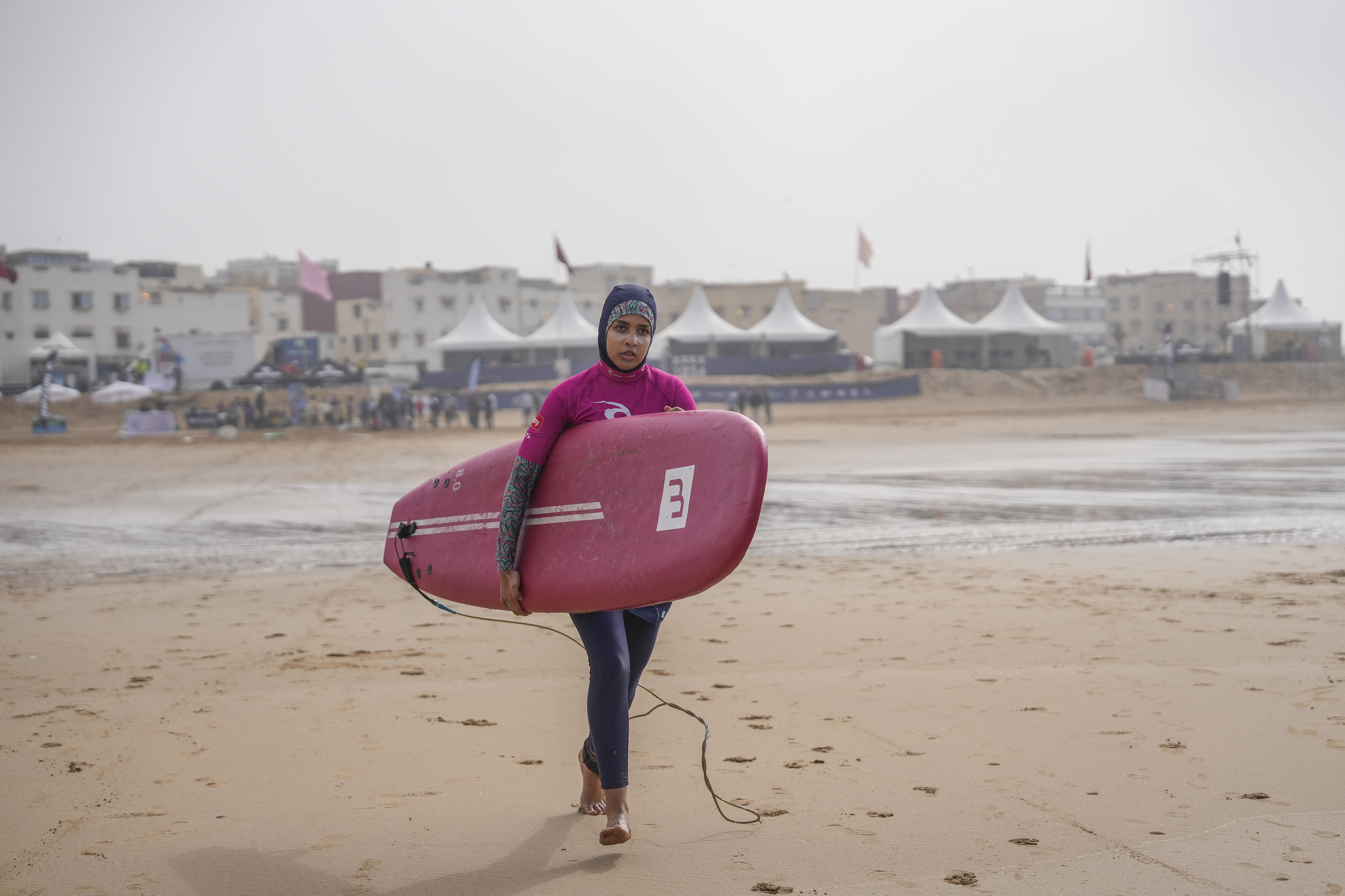 Una joven marroqu tabla en mano, surfea con su hiyab cubrindole la cabeza.