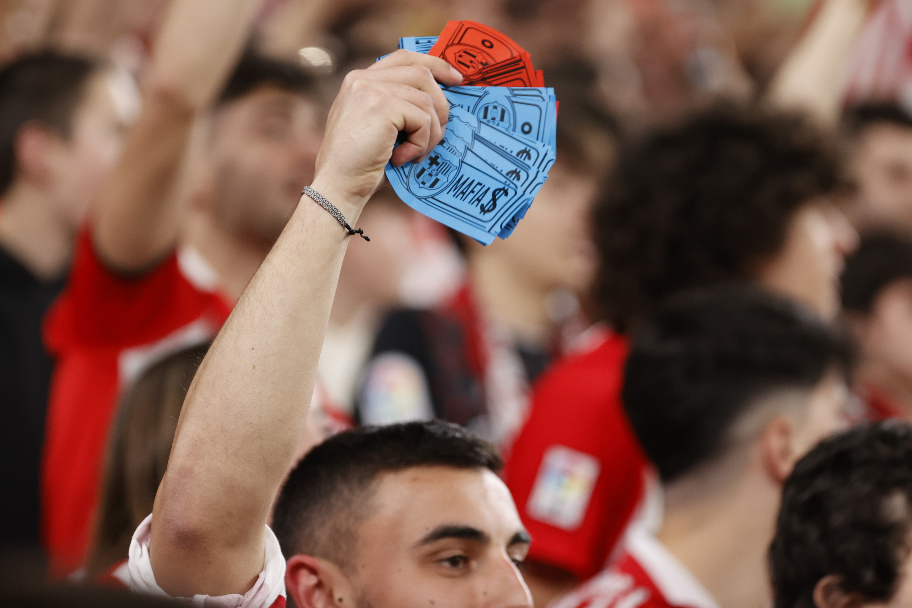 Un joven con billetes con el escudo del FC Barcelona y la palabra "mafia".