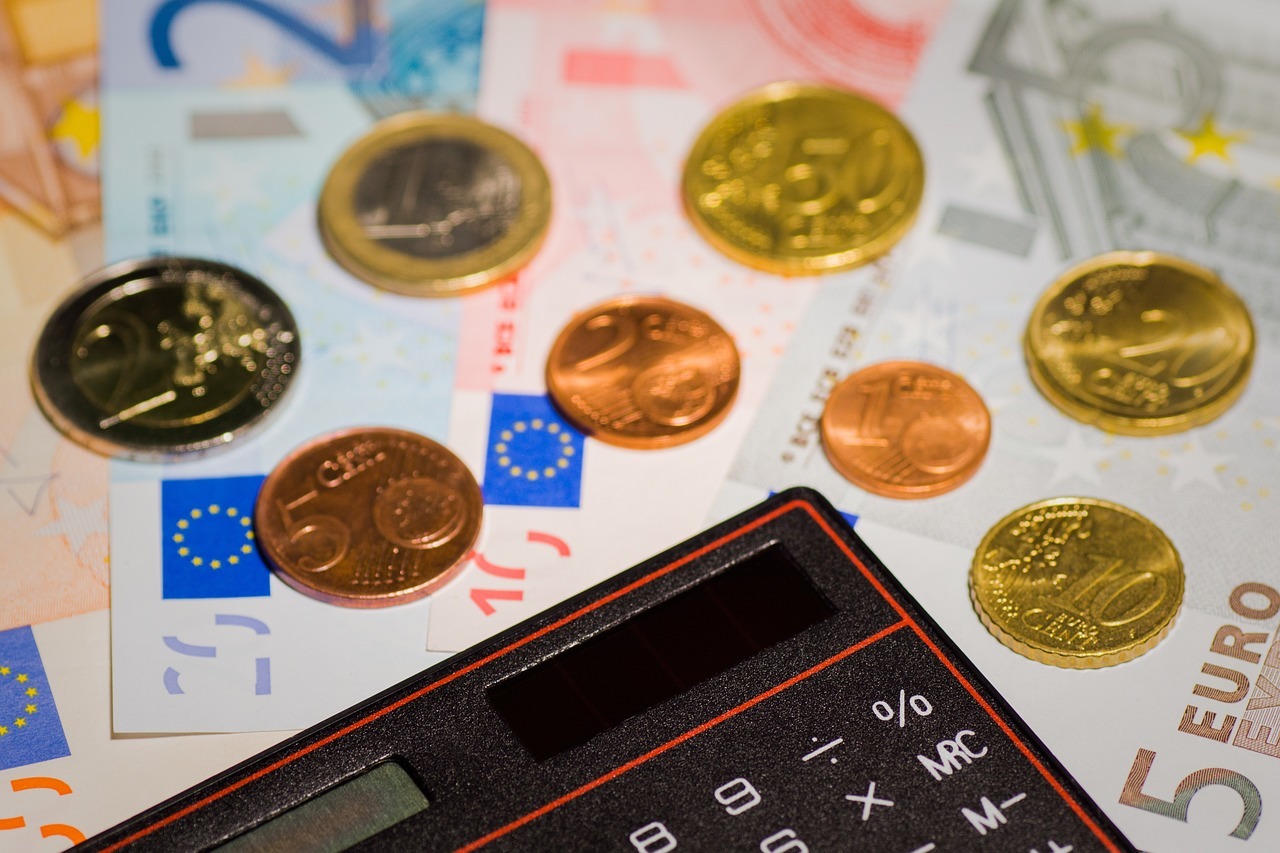 Una calculadora junto a monedas y billetes de euro.