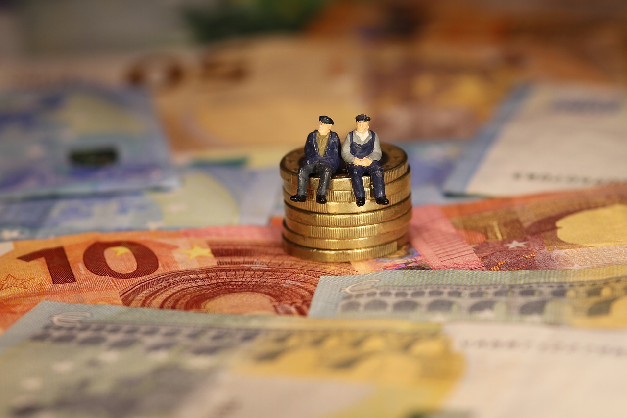 Dos figuritas que representan dos hombres mayores sentados sobre unas monedas de euro.