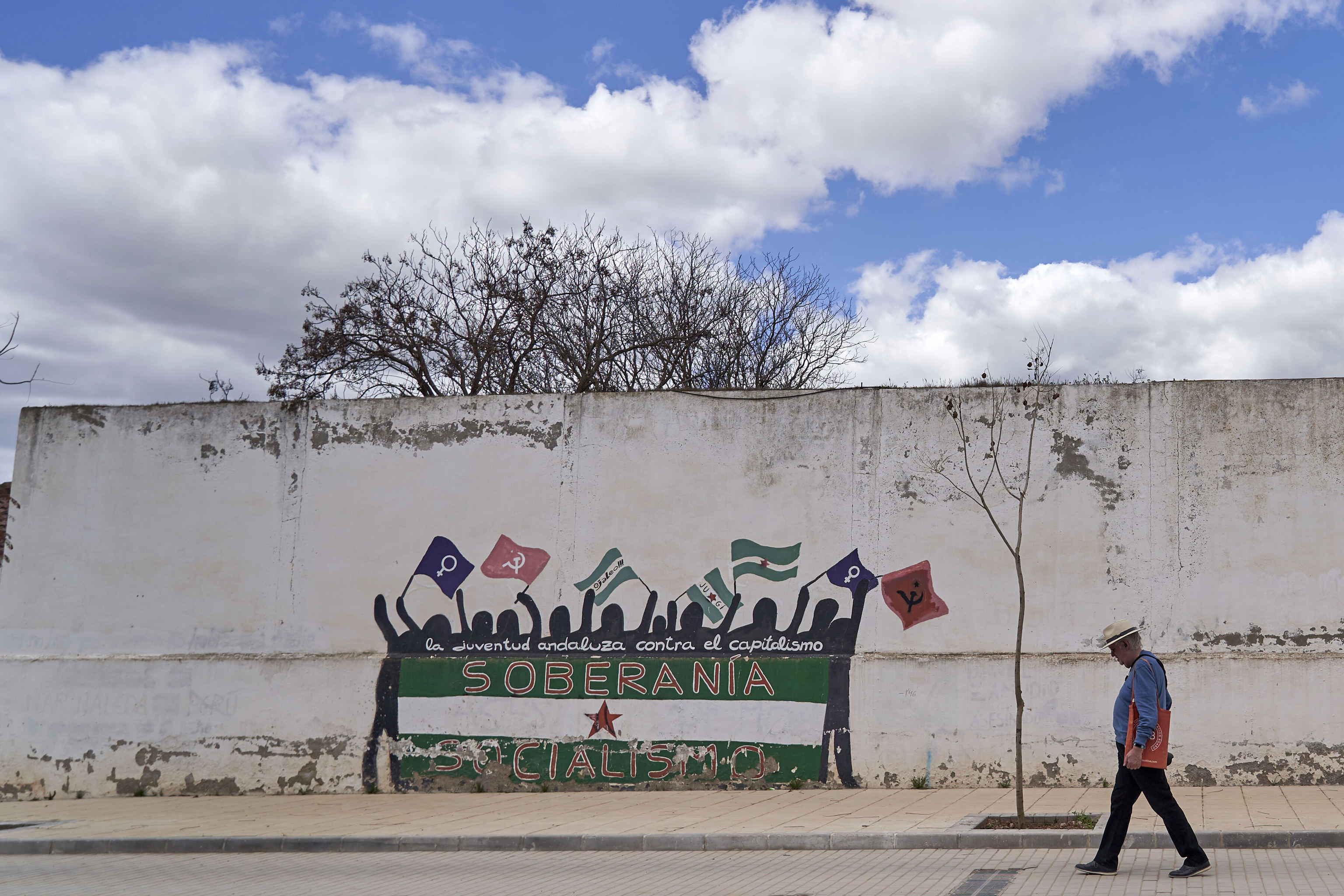 Un hombre pasa junto a un mural de temática comunista en la avenida principal de Marinaleda, la Avenida de la Libertad.