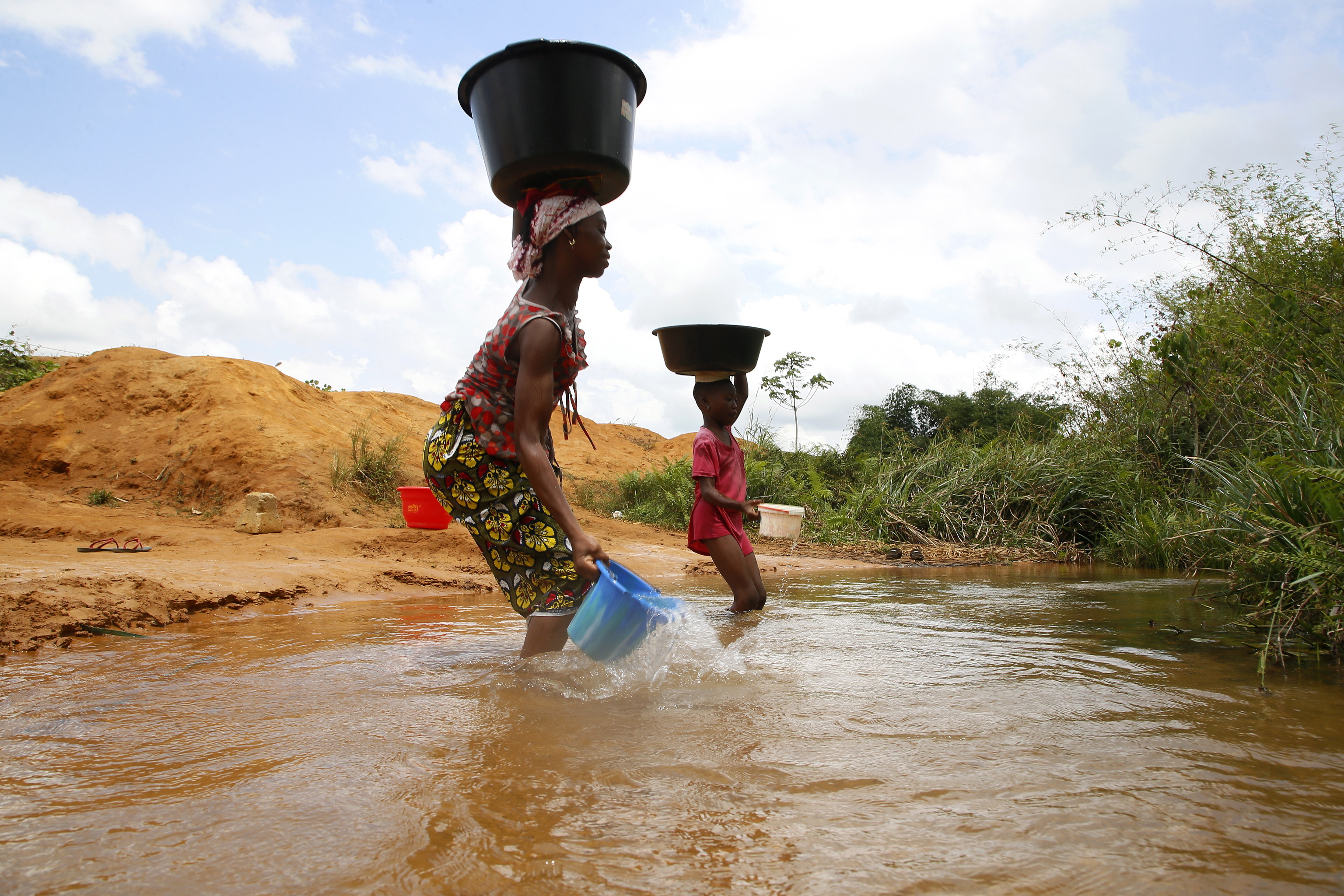 Una mujer llena un balde con  agua de ro en Abiyn, Costa de Marfil.
