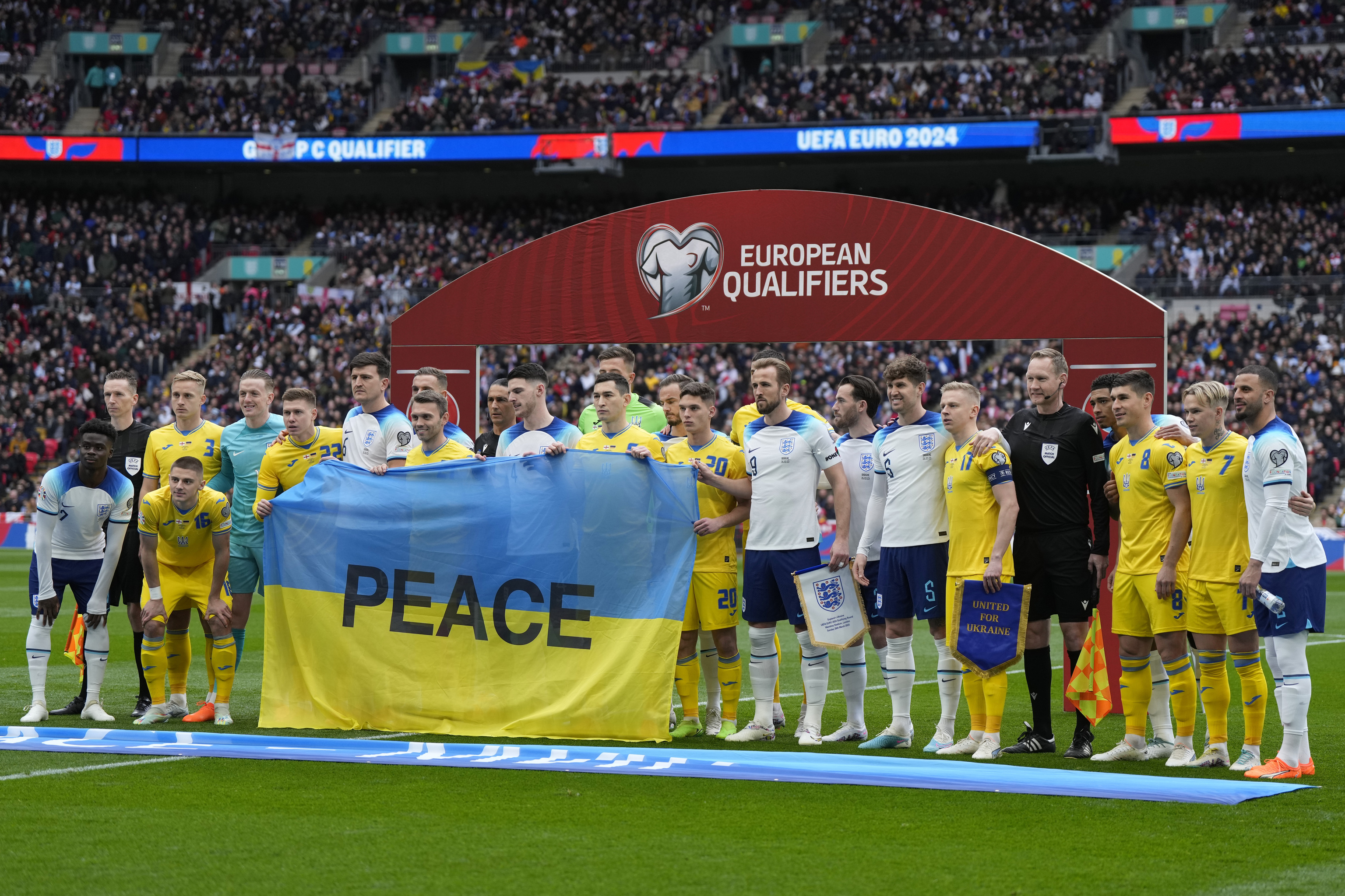 Jugadores de Inglaterra y Ucrania posan con la palabra 'Peace'.