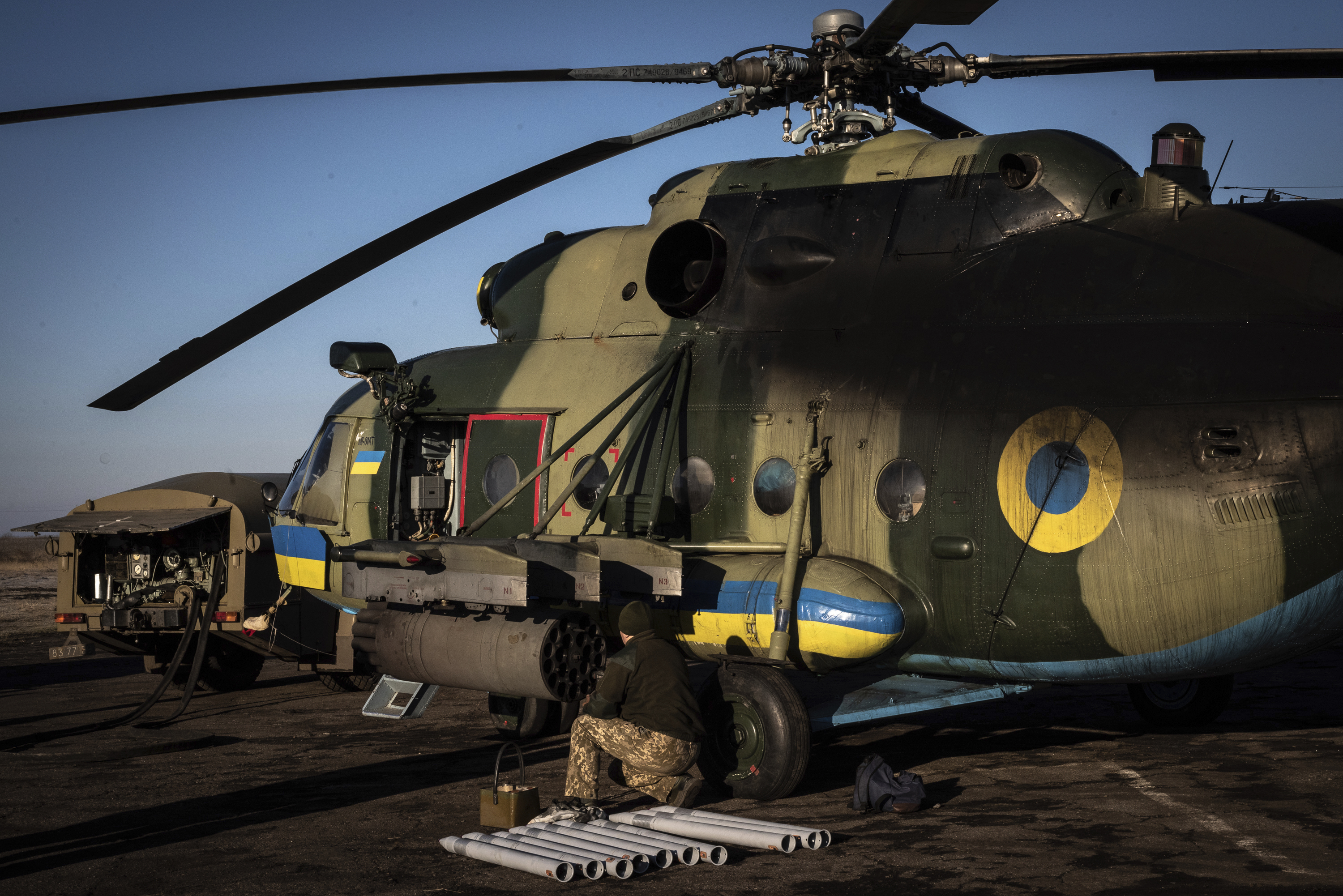 Un tripulante de un helicóptero ucraniano MI-8 prepara el lanzacohetes para una misión en Donbás.