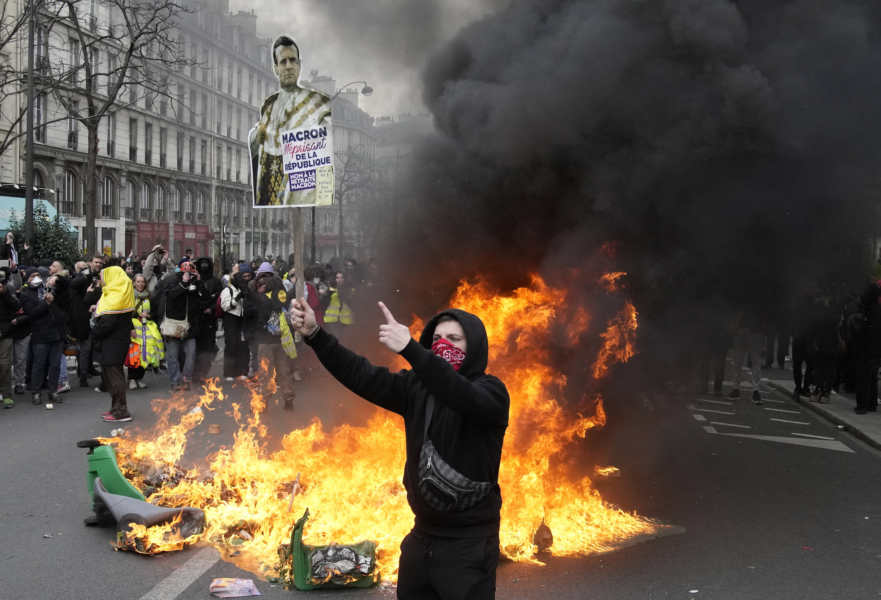Un manifestante sostiene una pancarta burlándose del presidente de Francia.