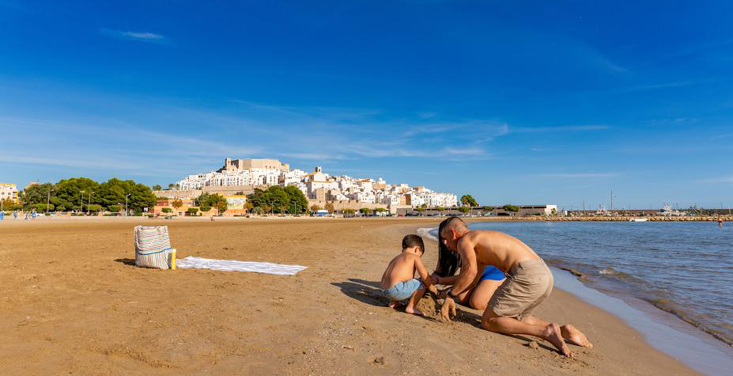 Una familia juega en la arena en una de las playas de Pescola.