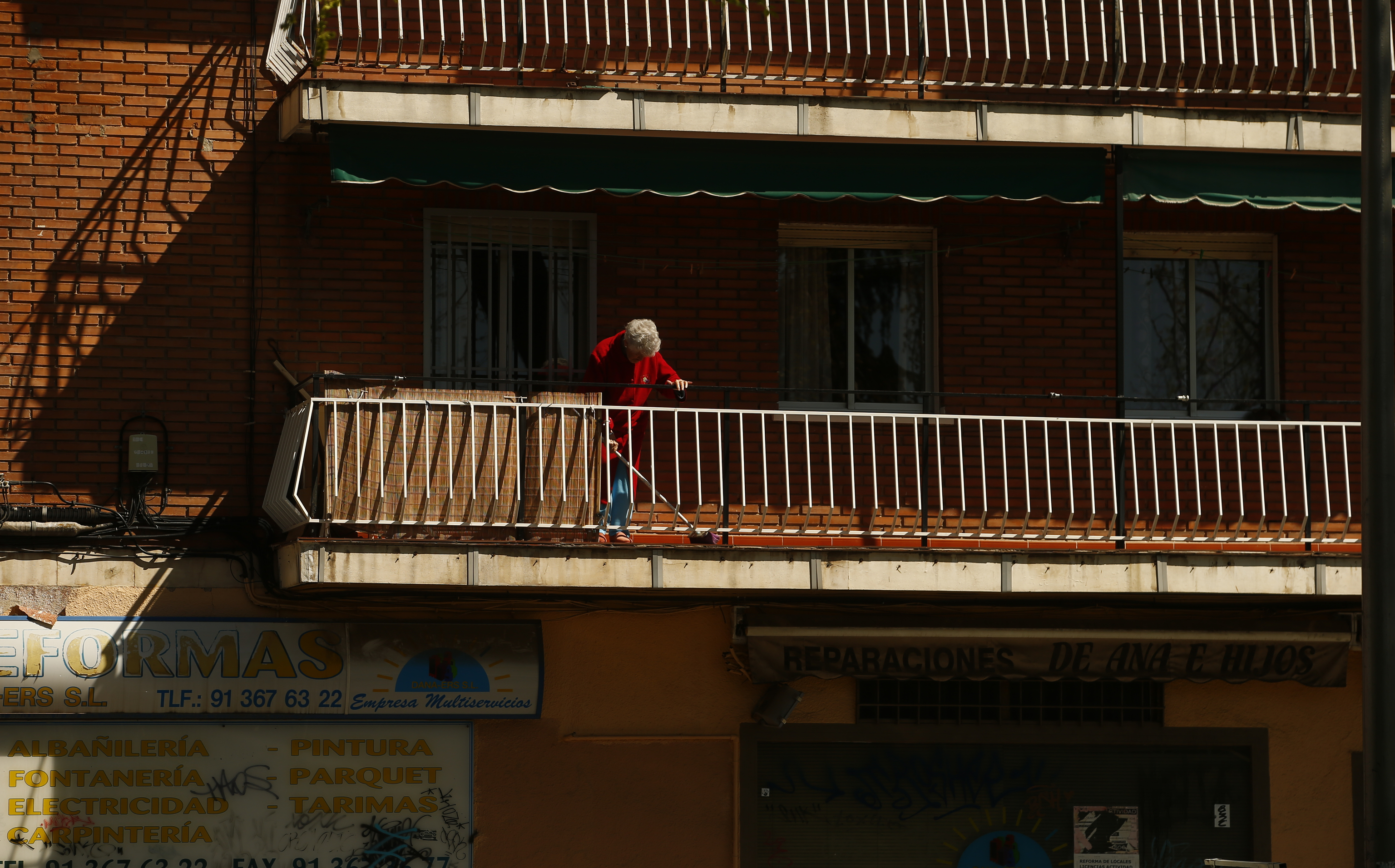 Una anciana friega su terraza.