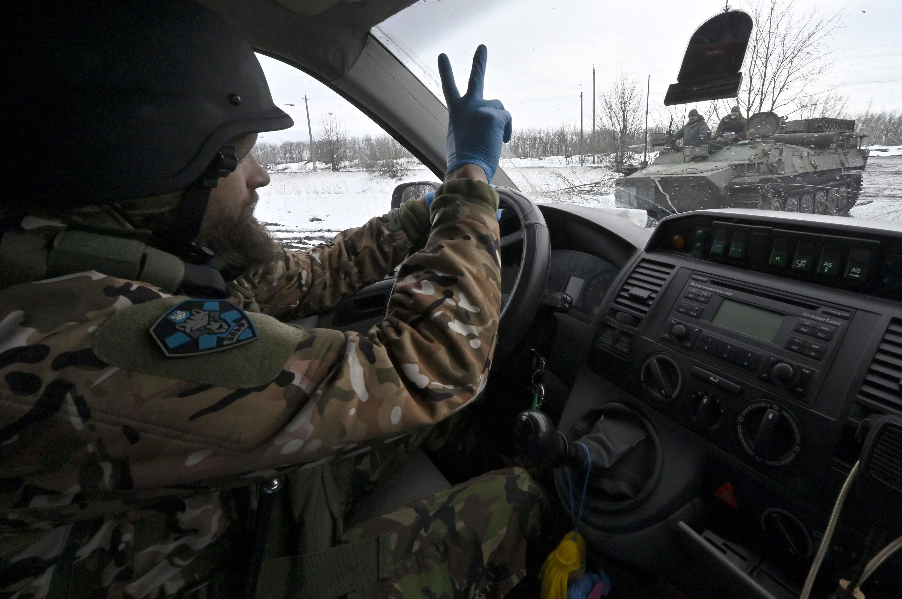 Un conductor de una ambulancia del Batallón de Lobos Da Vinci saluda a sus compañeros mientras conduce por una carretera cercana a la línea del frente cerca de Bajmut, en la región de Donetsk, el 1 de abril de 2023, en medio de la invasión rusa de Ucrania. - Las carreteras se han convertido en lodazales por la nieve derretida, lo que hace que el viaje sea lento. La ambulancia está cubierta de barro desde las ruedas hasta el techo.