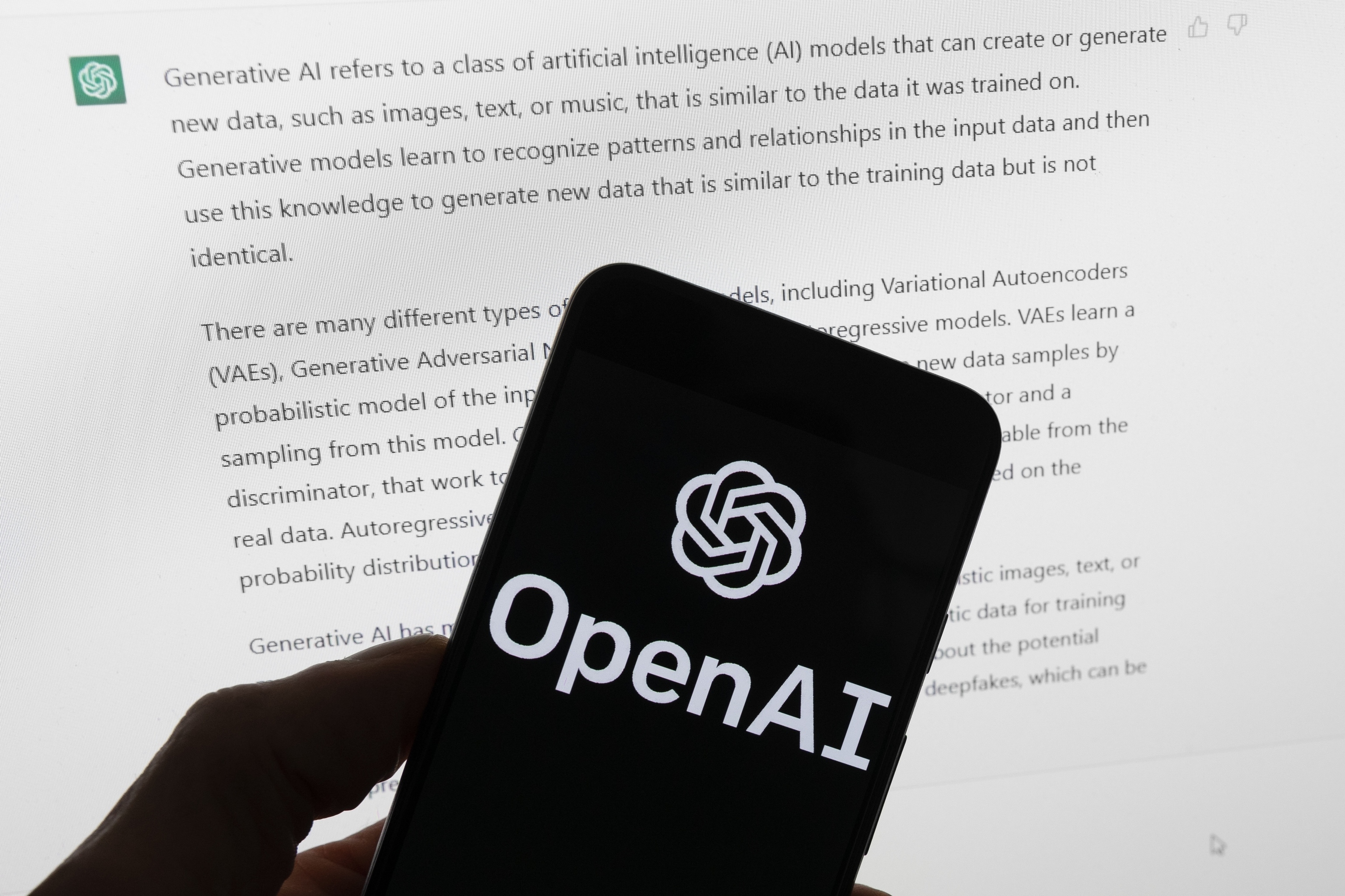 El logo de OpenAI, en un móvil frente a una pantalla.