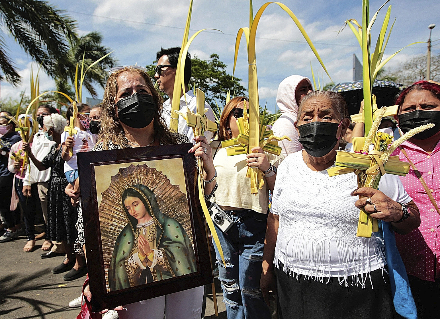 Varias personas sostienen cruces hechas de hojas de palma, en Managua.