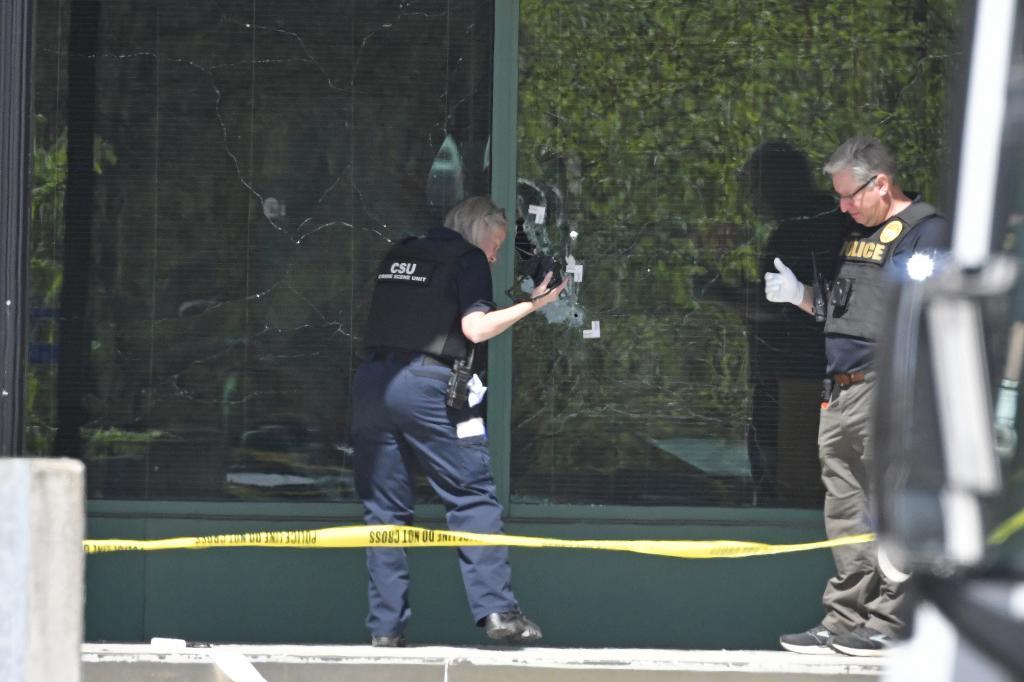 Un tcnico de la Polica Metropolitana de Louisville fotografa agujeros de bala en el cristal del banco.