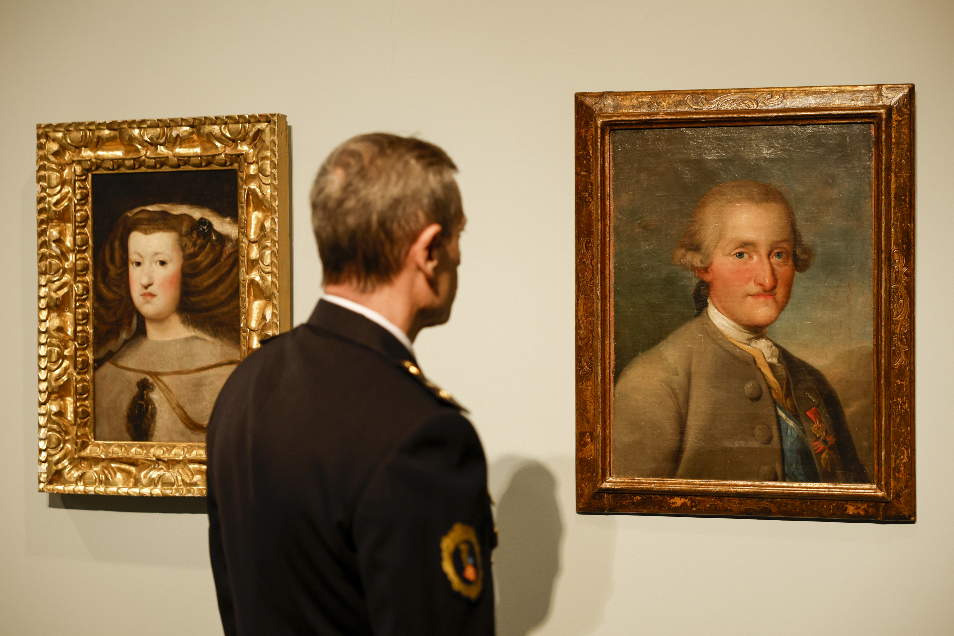 Un agente de la Unidad de Patrimonio de la Polica de la Generalitat contempla los cuadros falsificados de Velzquez "Mariana de Austria" (i) y de Goya "Carlos IV" durante la presentacin del informe.