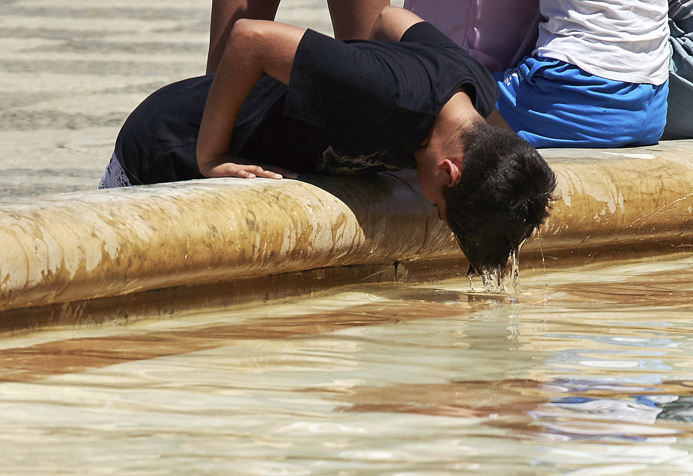 Un joven refrescndose en una fuente de Sevilla el martes