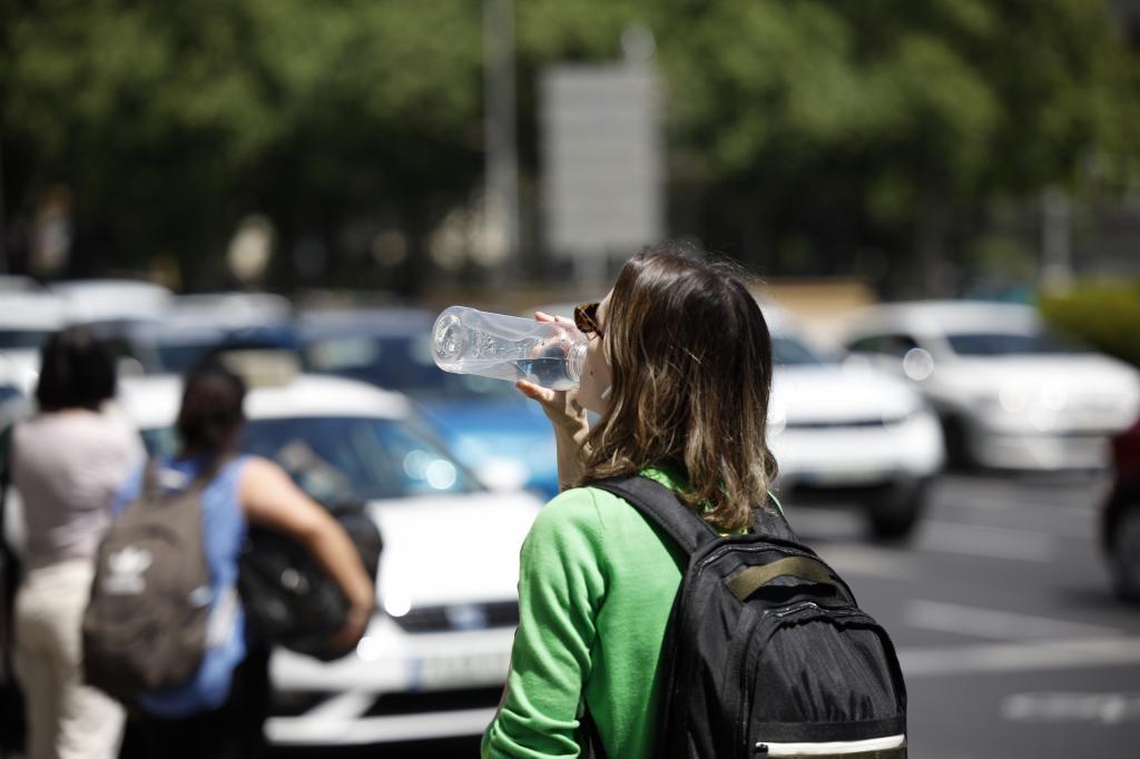 Una mujer bebe agua mientras hace turismo en Madrid.