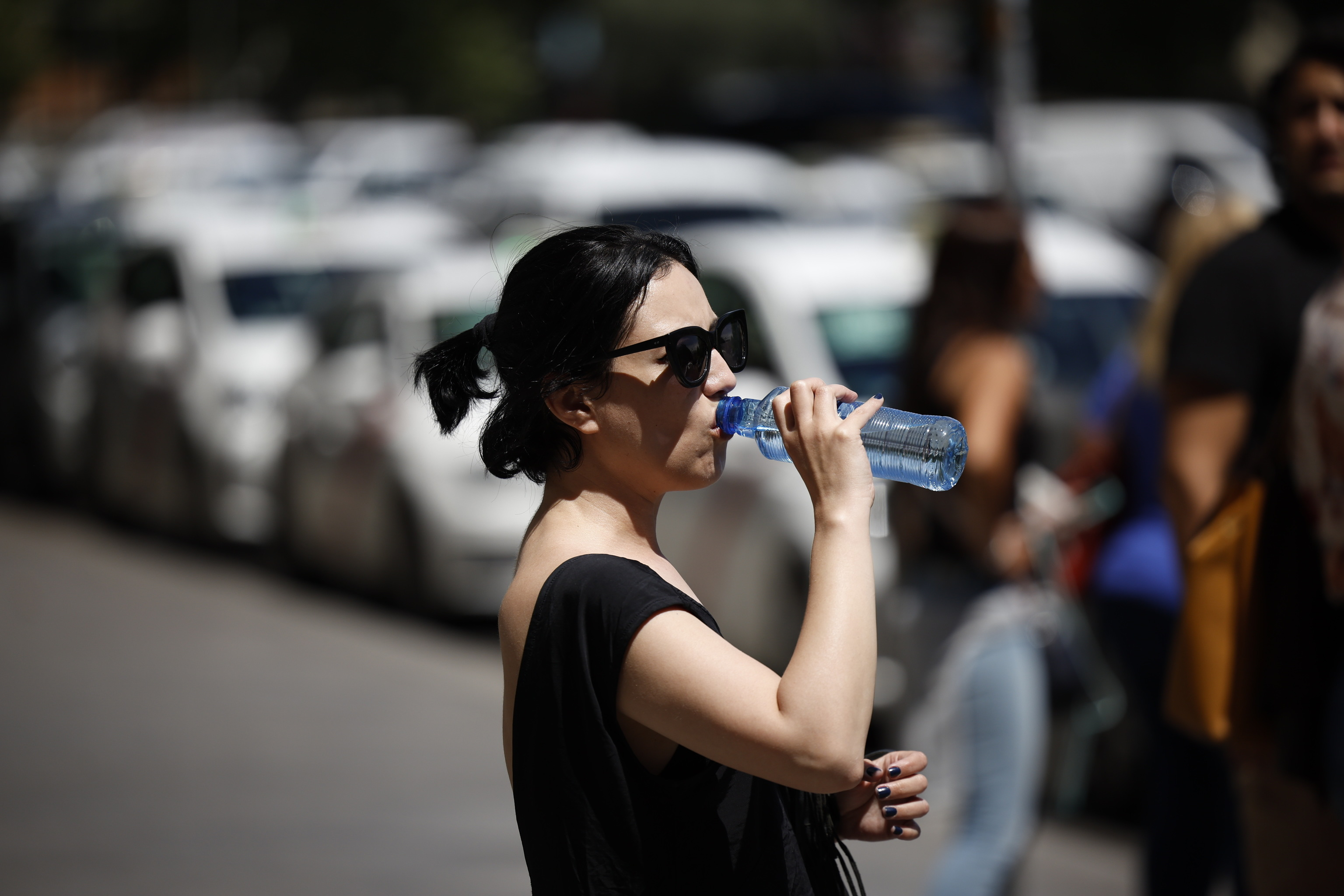 Una mujer bebe agua en la calle