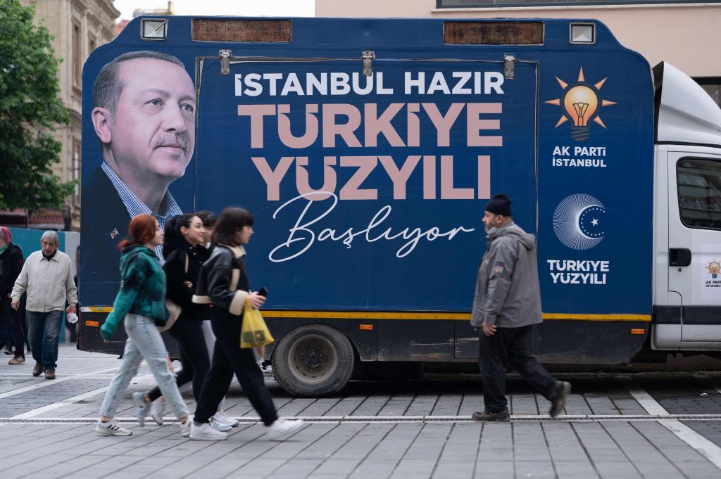Unos jvenes caminan junto a un camin electoral con una imagen del presidente Erdogan